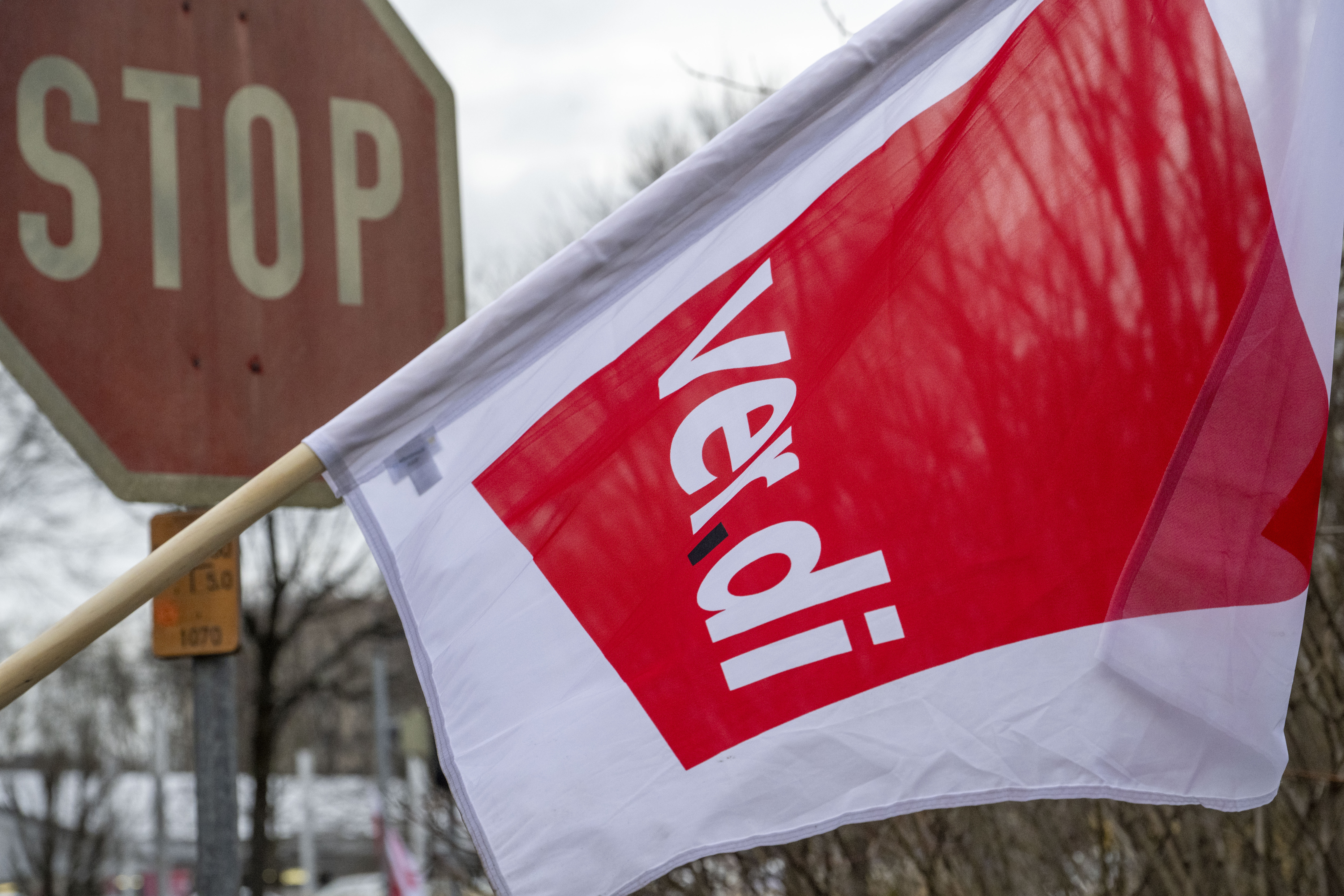 Eine Fahne der Gewerkschaft Verdi weht vor einem Stoppschild.