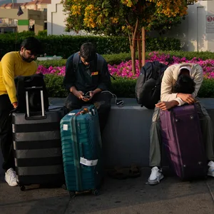 Passagiere, die durch die Schließung des internationalen Flughafens in Dubai gestrandet sind, warten auf dem Flughafenparkplatz.