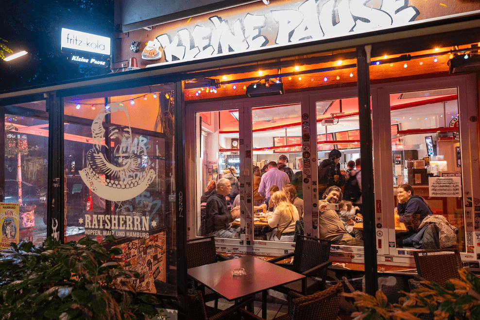 Blick in einen gut gefüllten Imbiss „Kleine Pause“ am Abend, Gäste sitzen dicht gedrängt an Tischen auf St. Pauli (Archivbild).