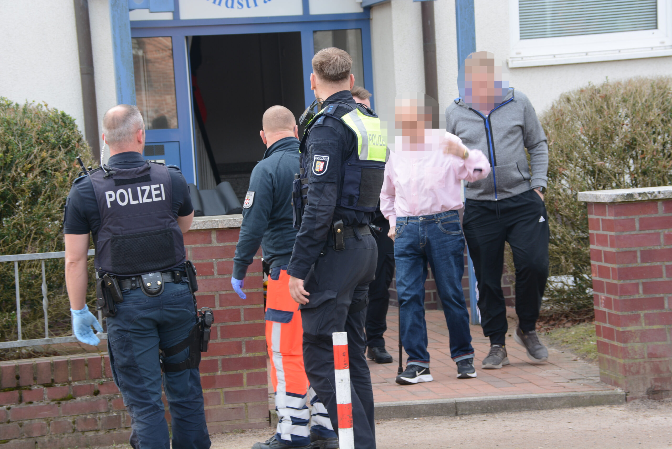 Polizisten stehen vor einem Wohnhaus.