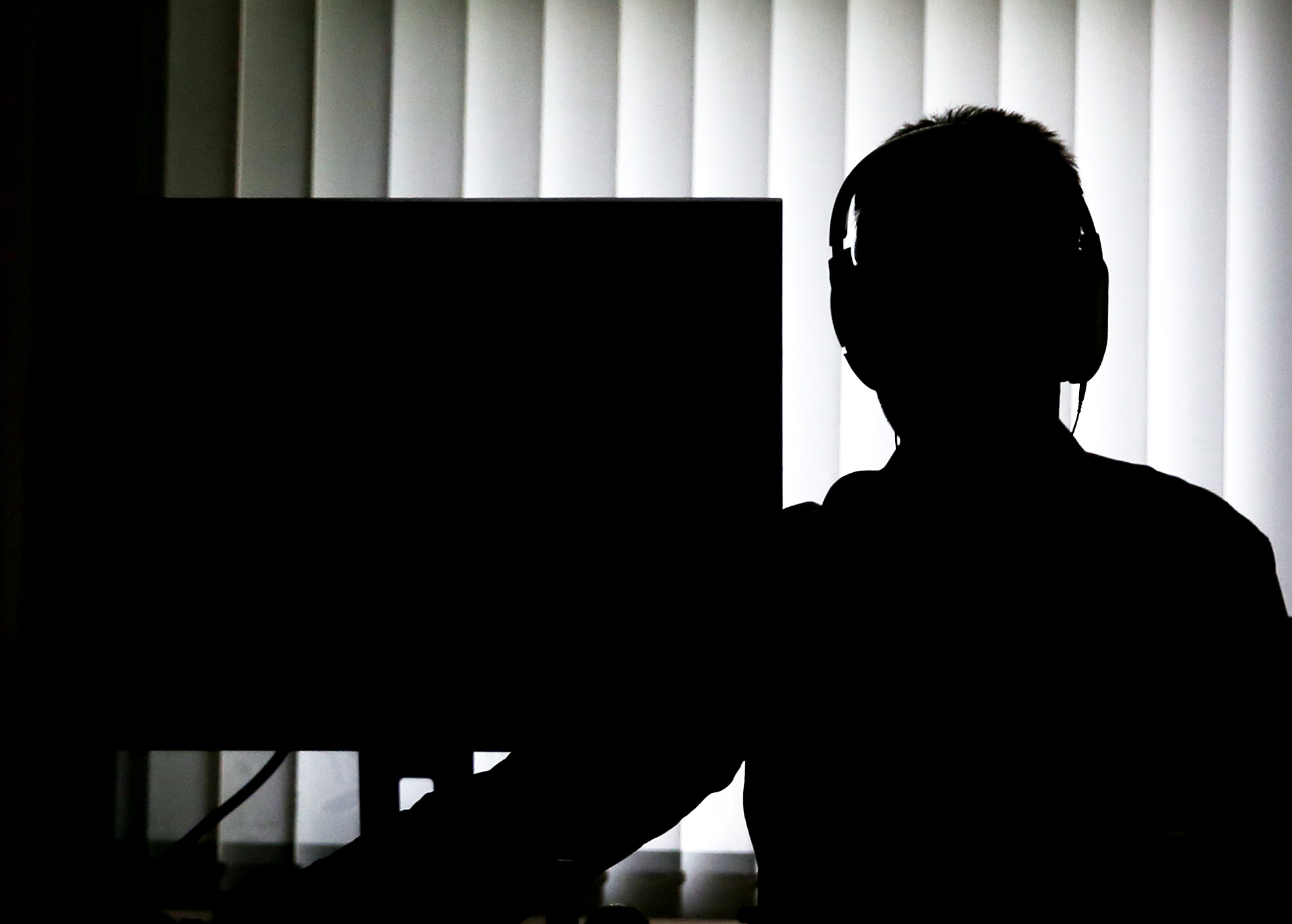 Ein Beamter sitzt mit Kopfhörern vor einem Computer in einem Büro.
