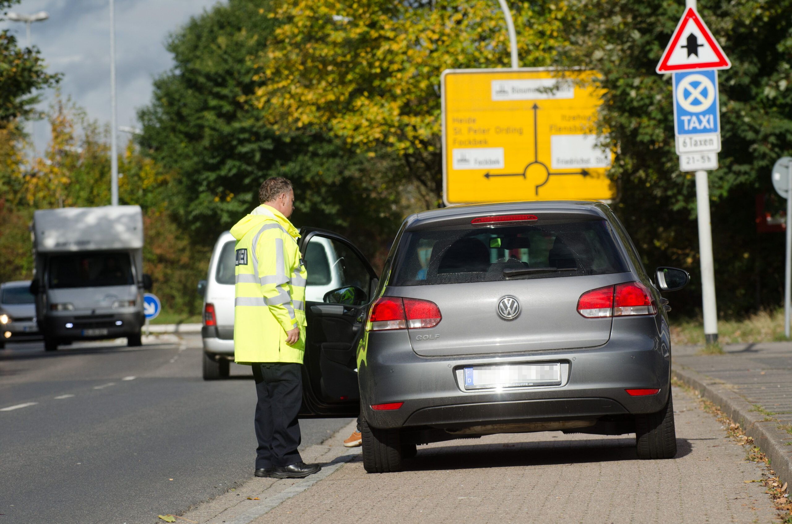 Ein Polizist kontrolliert ein graues Auto.
