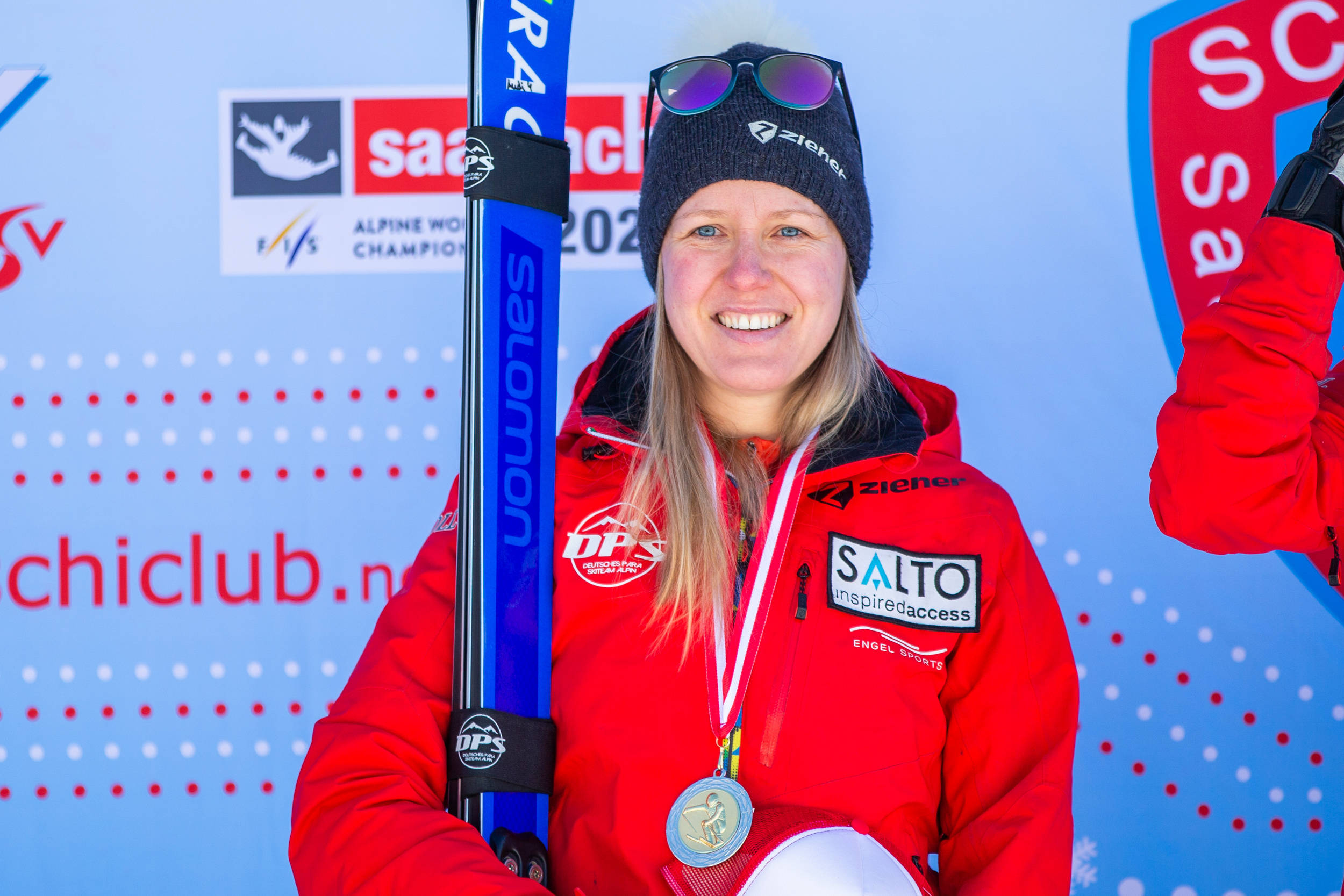 Andrea Rothfuss lächelt bei den Paralympics in die Kamera mit ihren Skiern in der Hand.