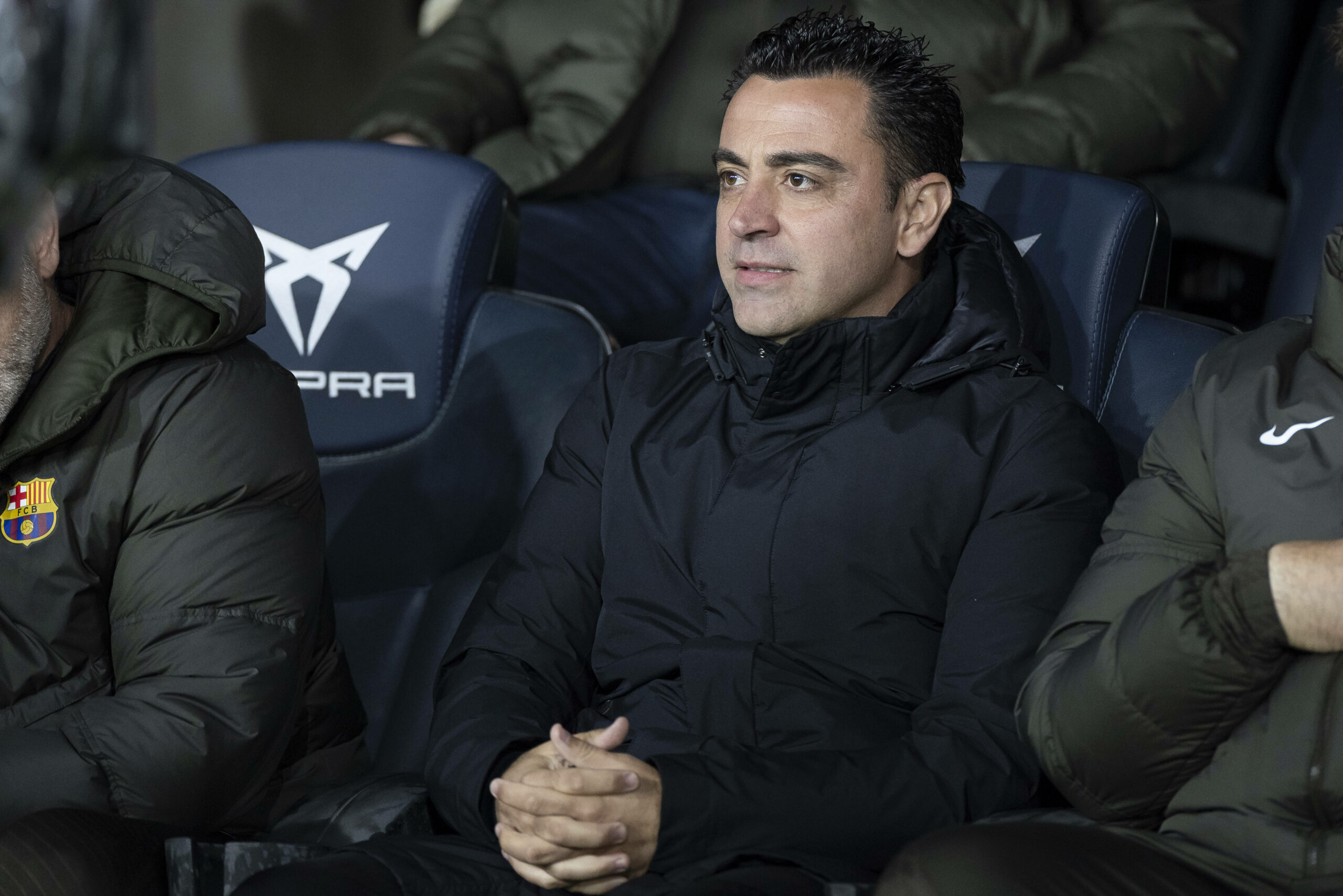 Xavi Hernandez sitzt mit verschränkten Händen auf einer Bank und schaut geradeaus.