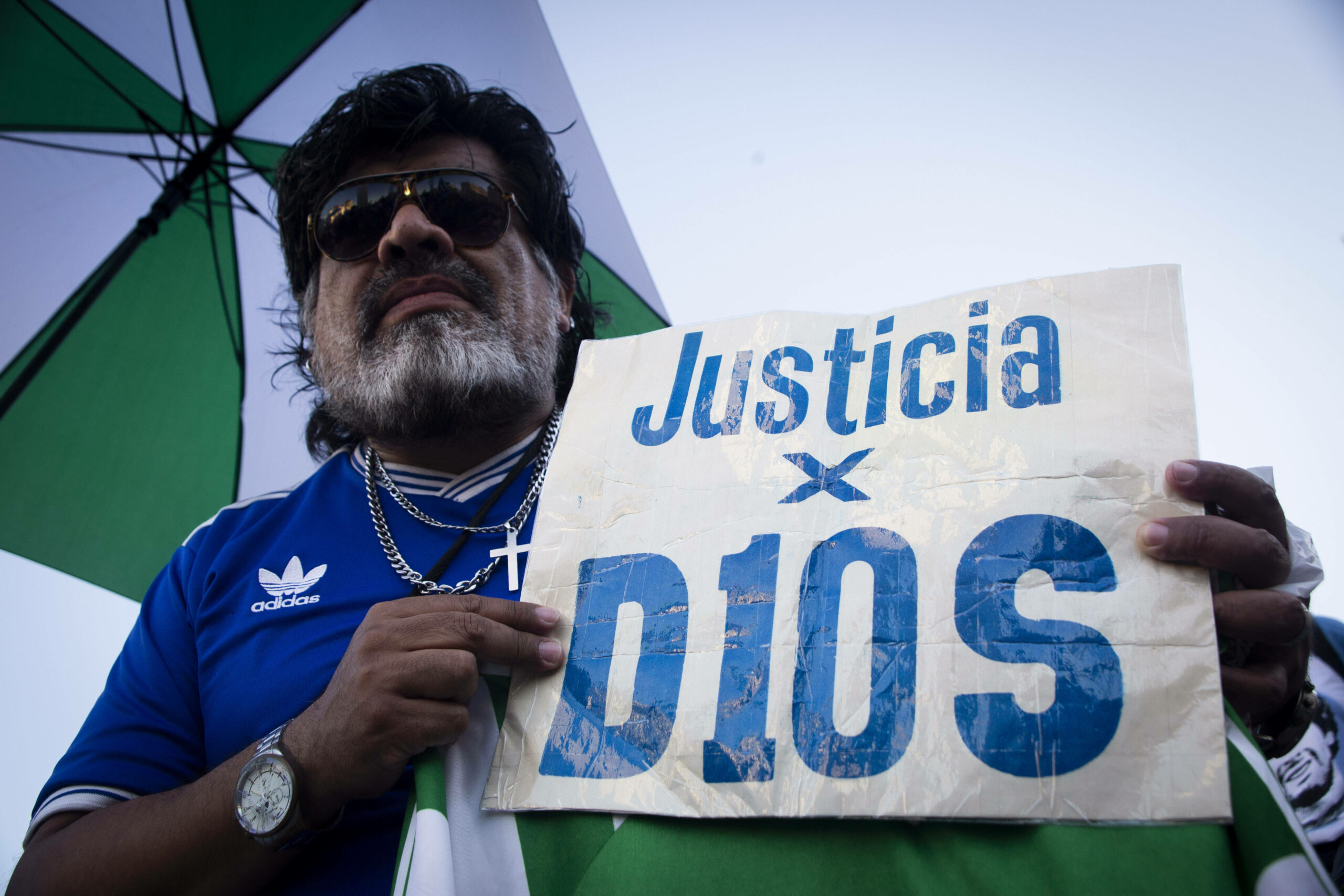 Ein Mann hält ein Schild in den Händen mit der Aufschrift „Justicia x Dios“.