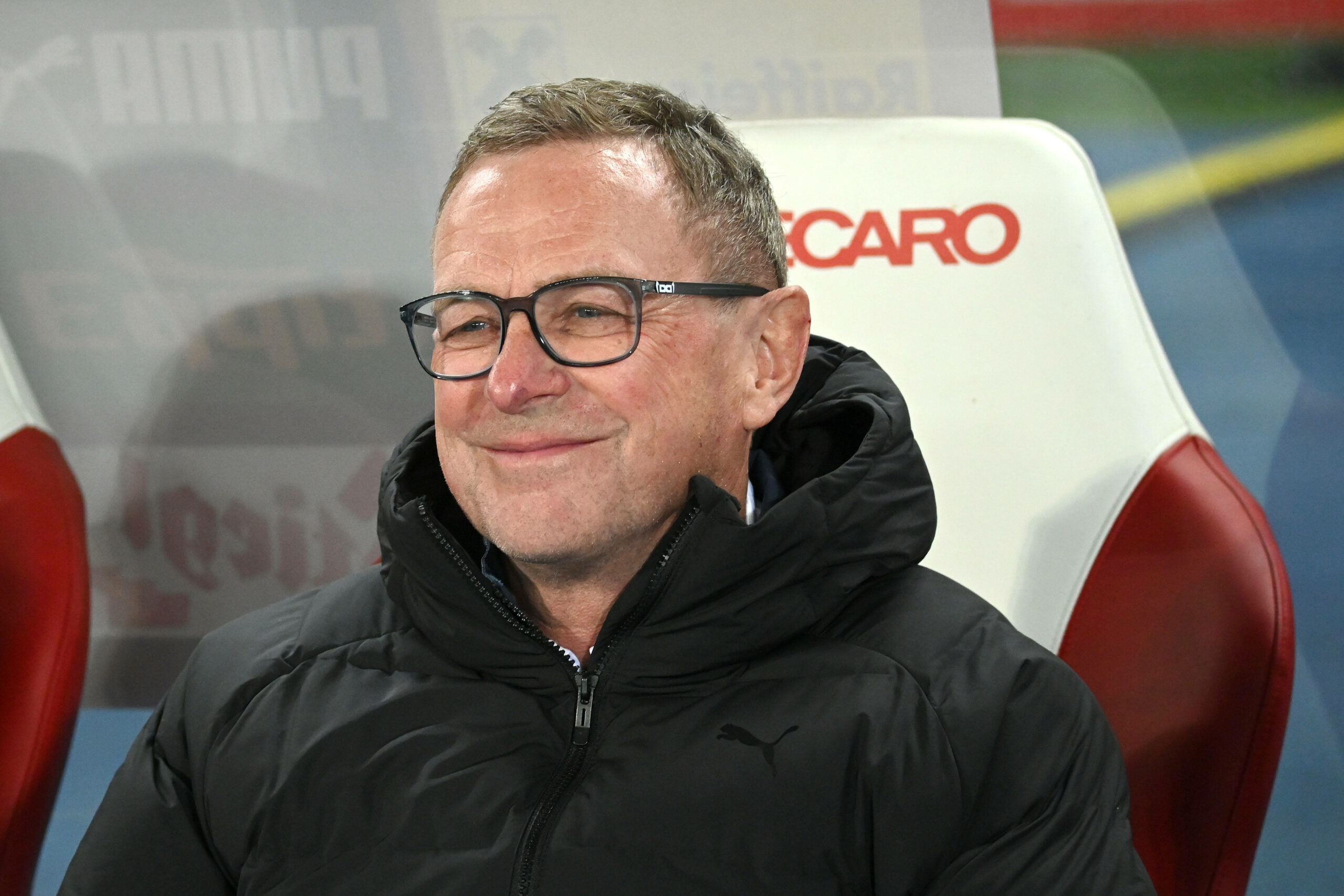 Ralf Rangnick lacht auf der Bank während eines Länderspiels.