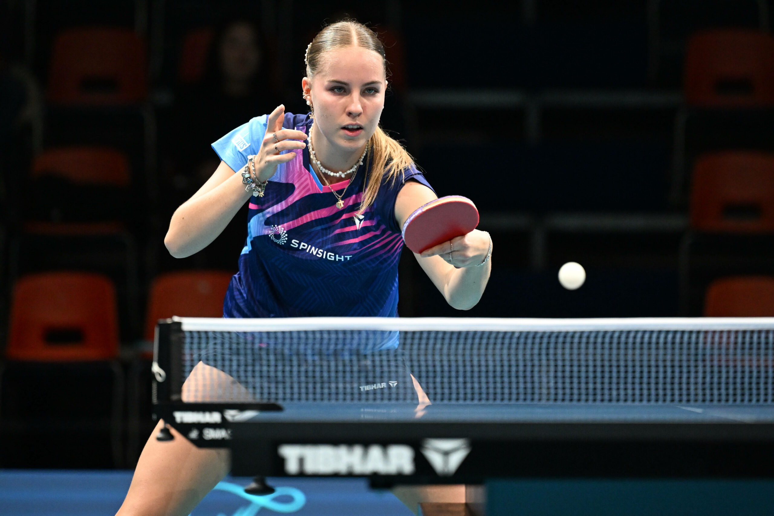 Tischtennisspielerin hat einen ankommenden Ball fest im Blick und holt zum Schlag aus.