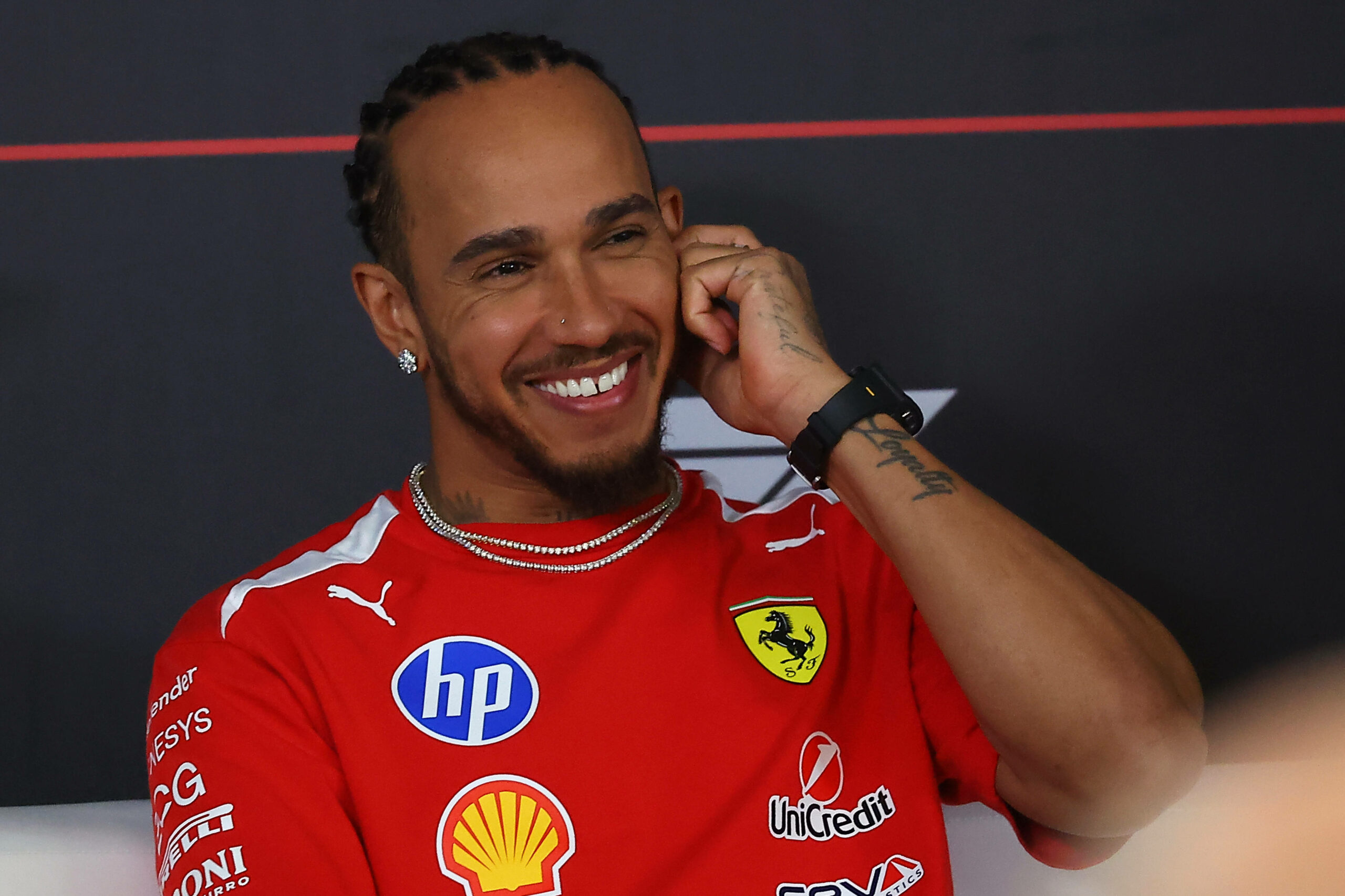 Lewis Hamilton in Bekleidung von Ferrari lächelt bei einem Interview.