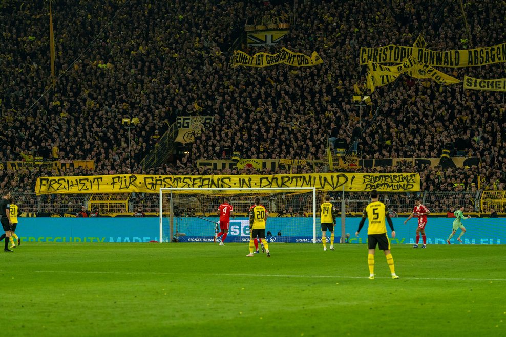 Fans des BVB halten ein Banner mit dem Schriftzug „Freiheit für Gästefans in Dortmund“ hoch.
