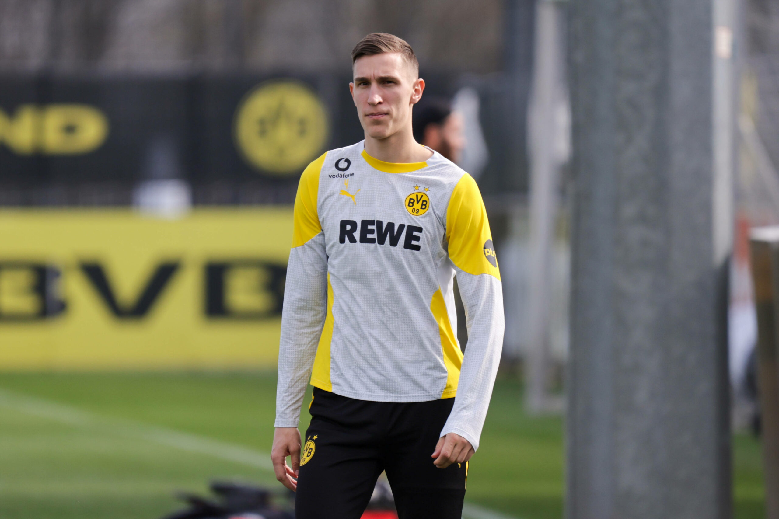 Nico Schlotterbeck steht im Trainingsanzug vom BVB auf einem Rasenplatz.
