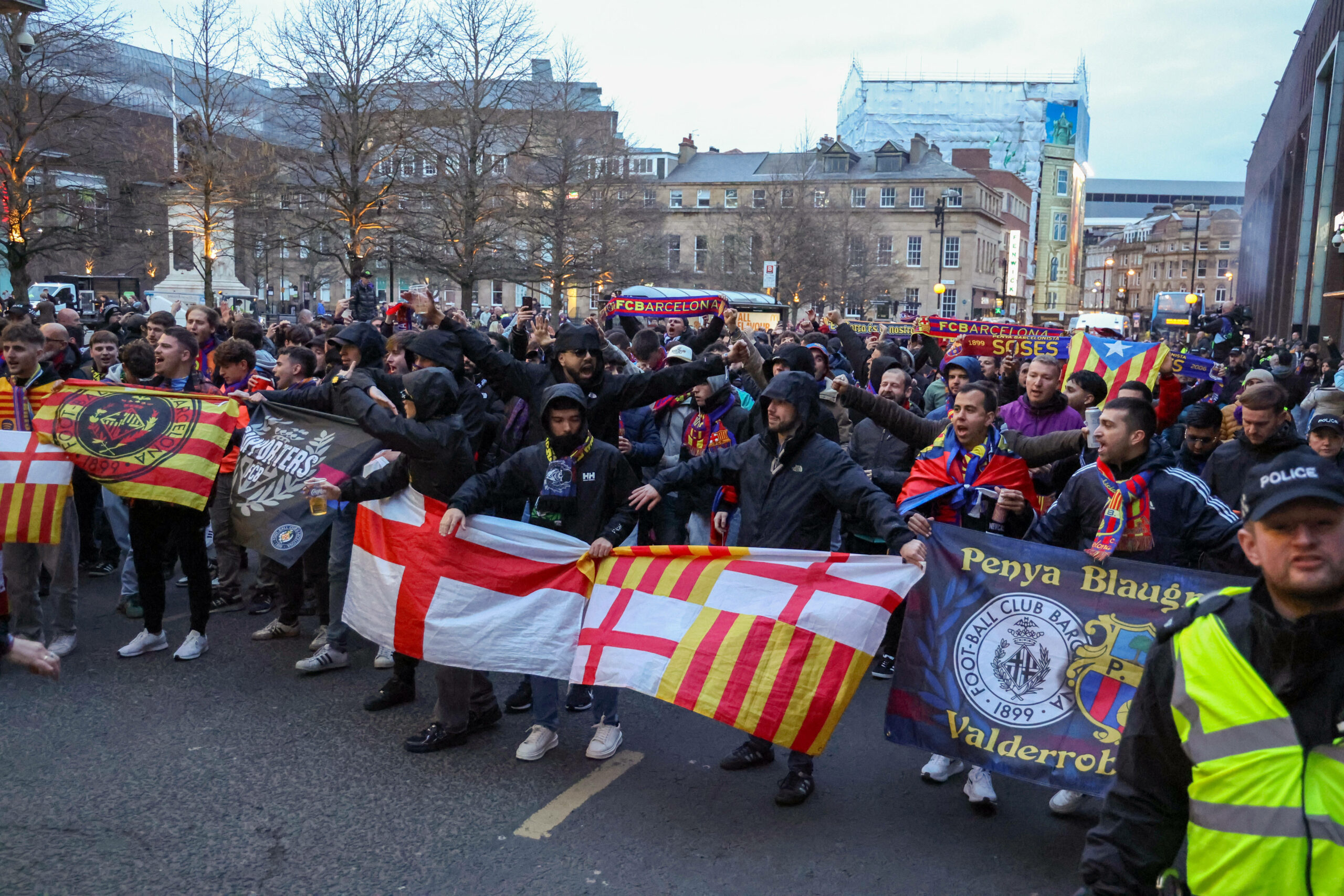 Fans des FC Barcelona marschieren durch eine Innenstadt und halten Fahnen in den Händen.