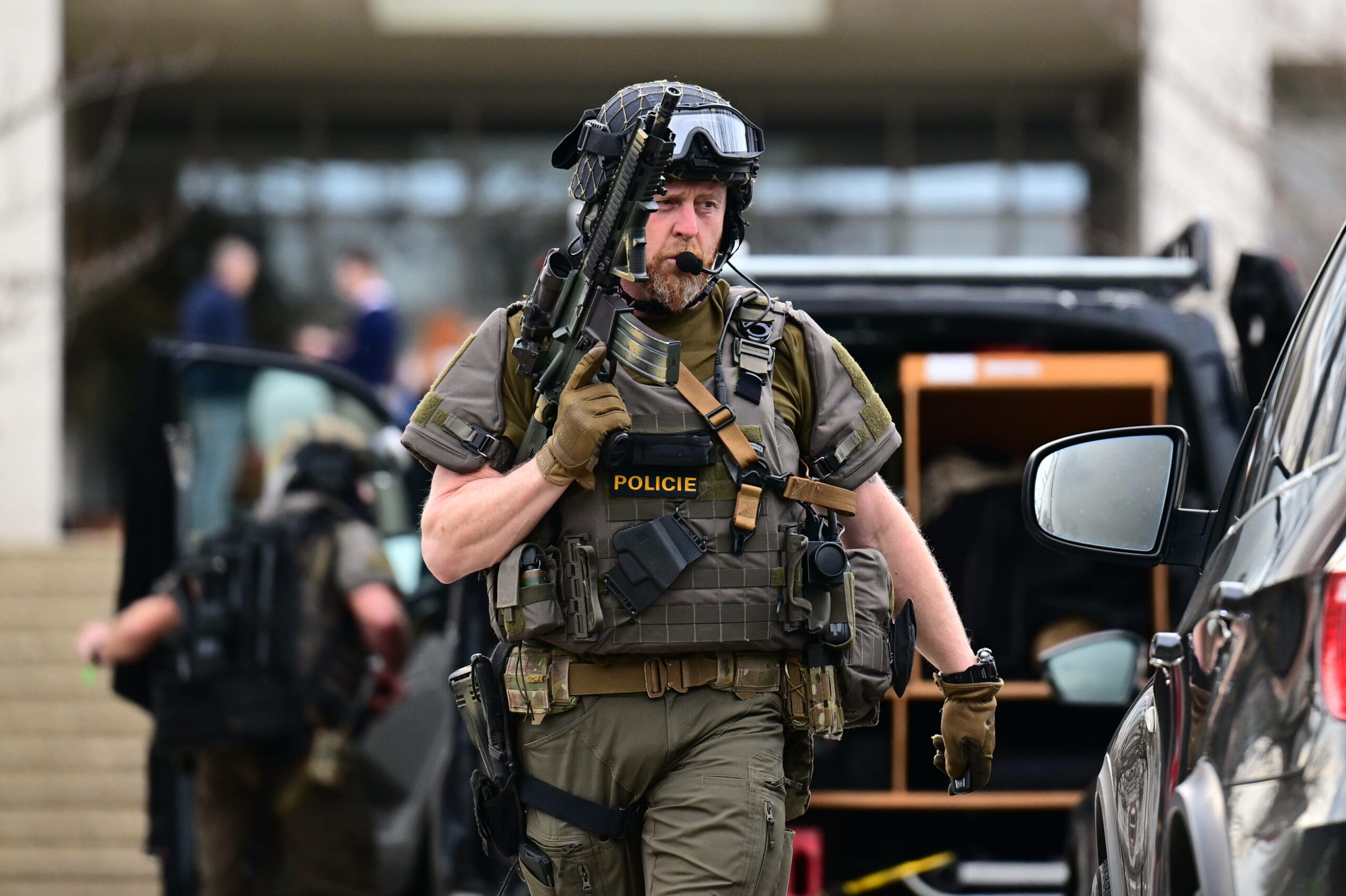 Ein bewaffneter tschechischer Polizist läuft neben einem Auto