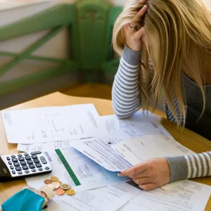 Frau mit Rechnungen, stützt den Kopf auf