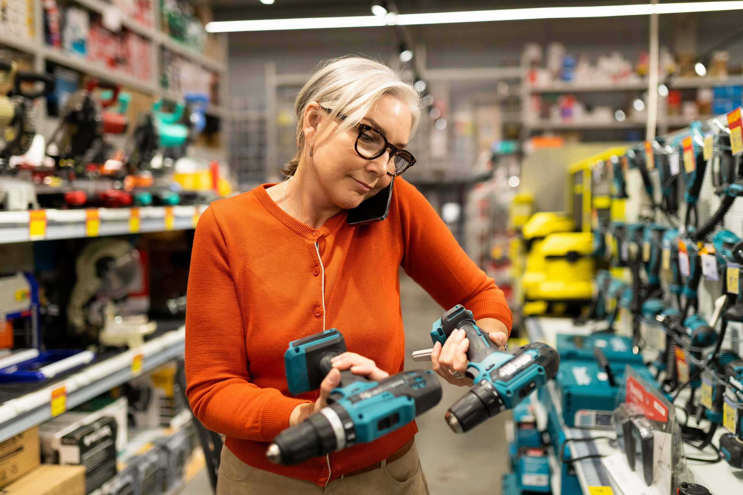 Eine Frau schaut sich Werkzeuge an, während sie telefoniert. (Symbolbild)
