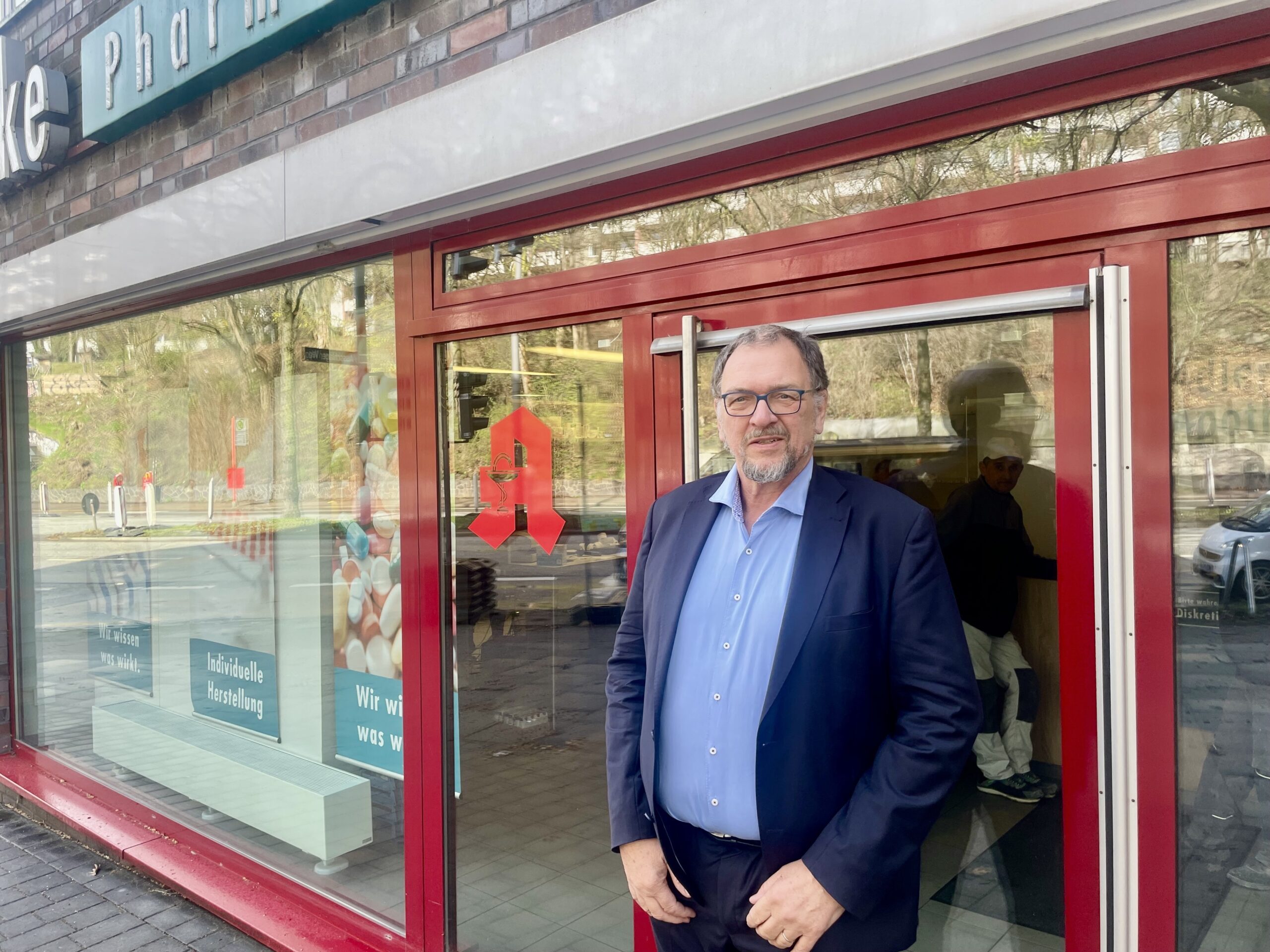 Mann in hellblauem Hemd vor Apotheke