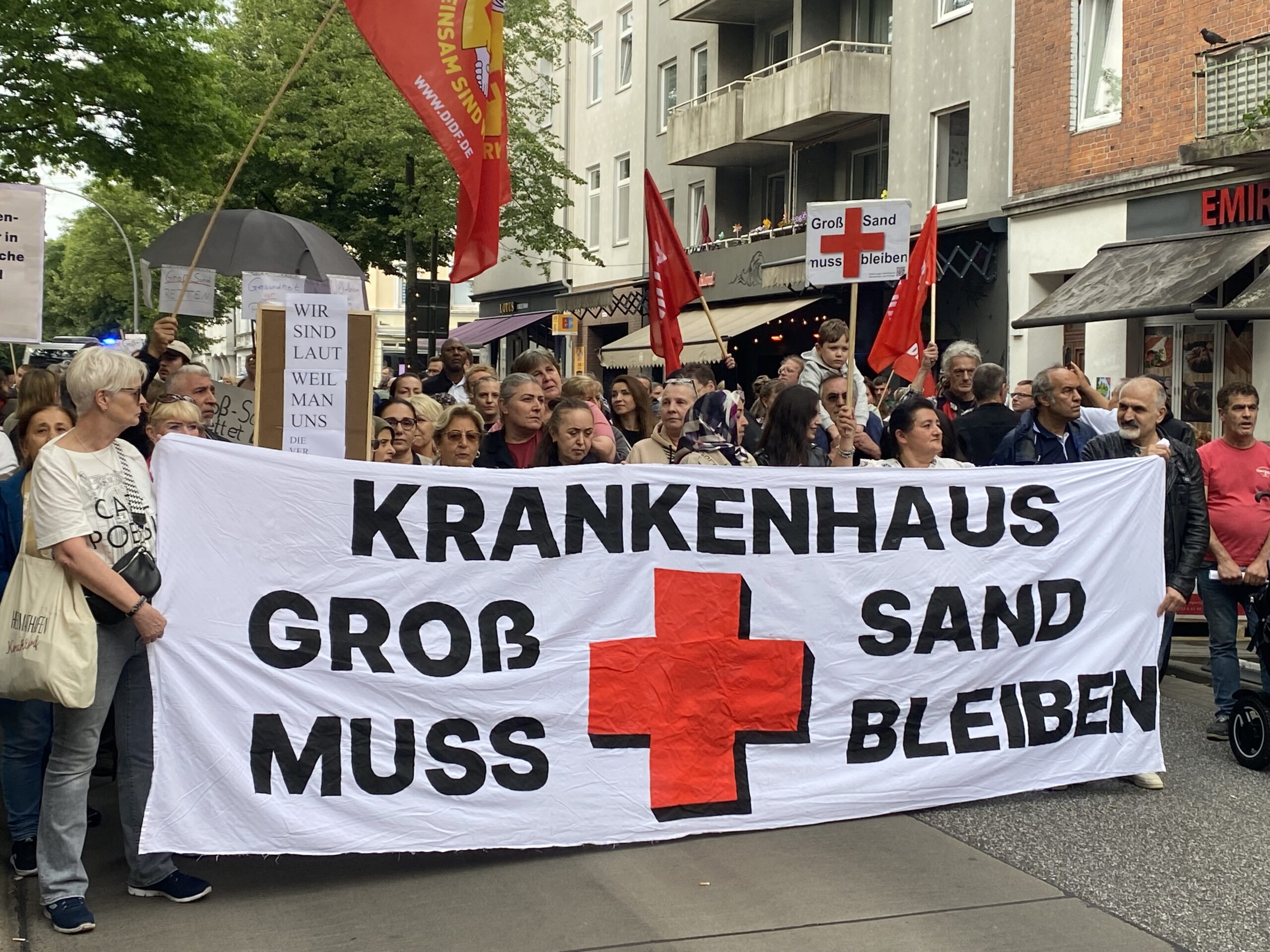 Demonstranten tragen ein Banner mit der Aufschrift: „Krankenhaus Groß-Sand muss bleiben“