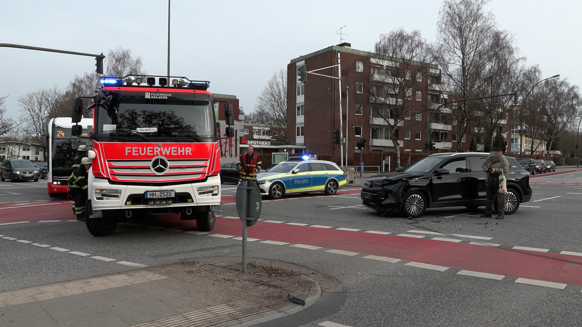Ein Feuerwehrwagen steht neben einem verunfallten Auto auf einer Kreuzung.