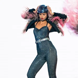 Kandidatin Lola (19) steht auf dem Laufsteg, die Hände am Glitzerhelm.