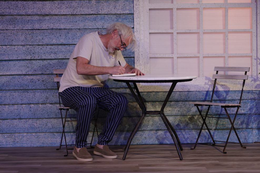 Ein Mann sitzt an einem Gartentisch.