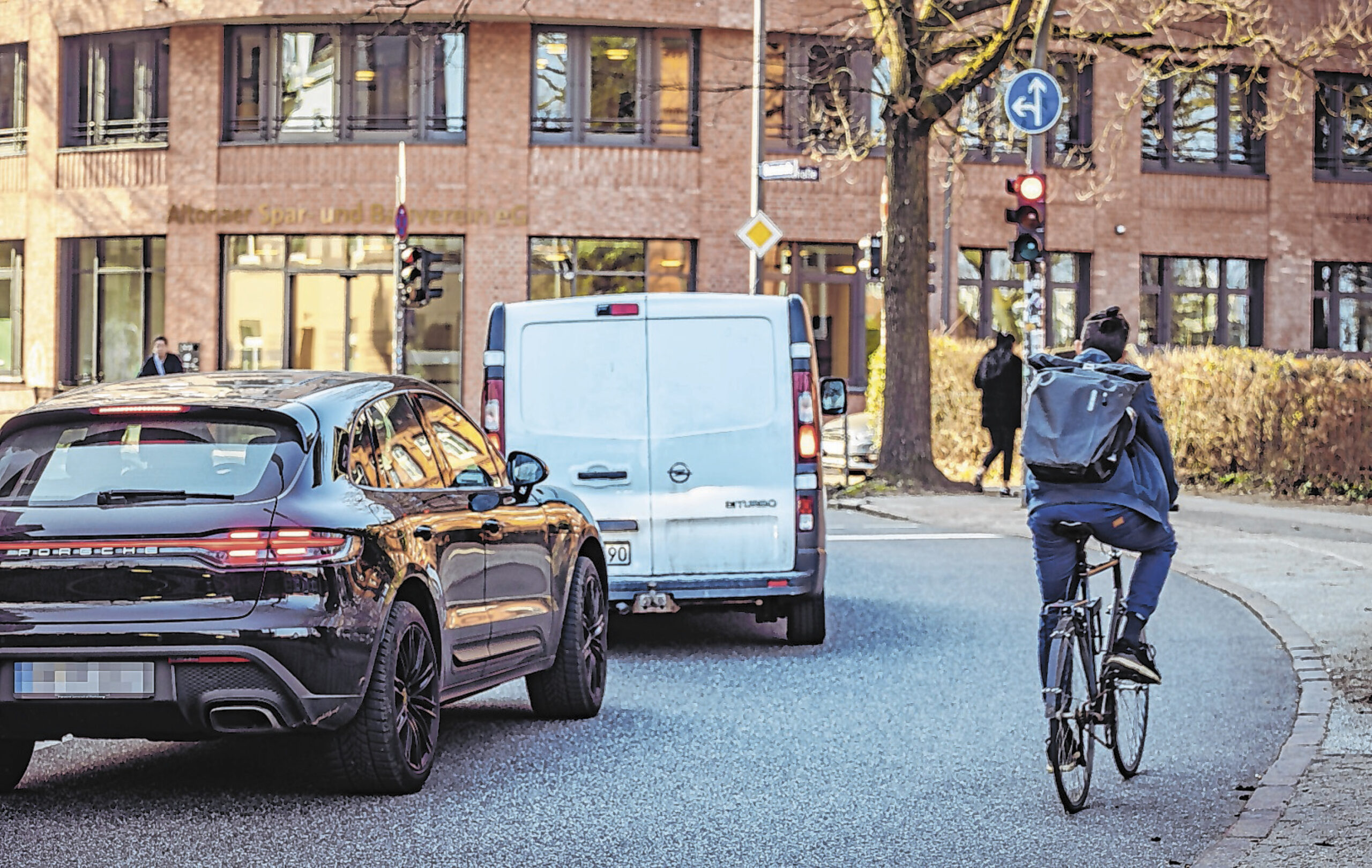 Fahrradfahrer überholt stehende Autos an roter Ampel