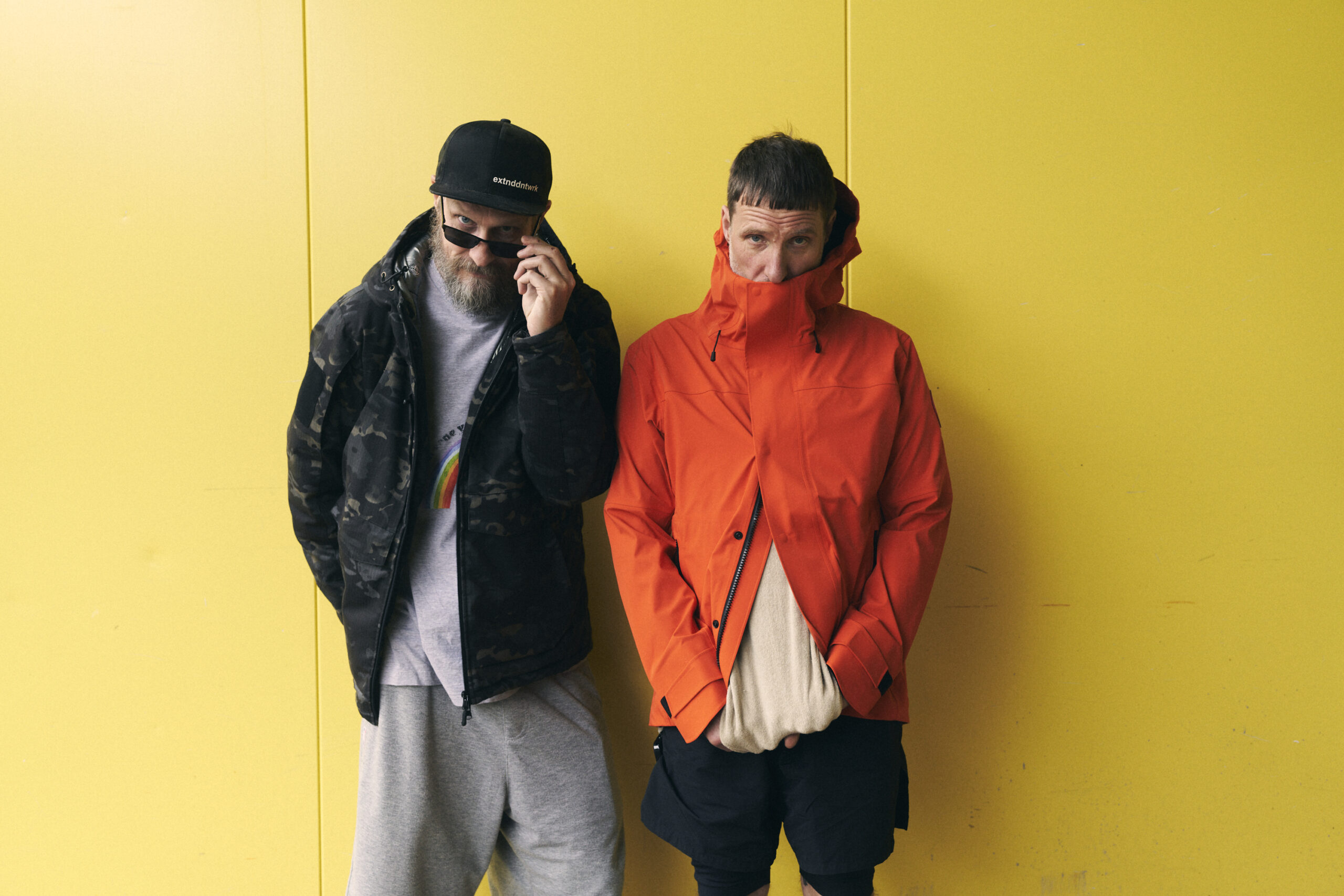 Die beiden Männer stehen vor einem gelben Hintergrund