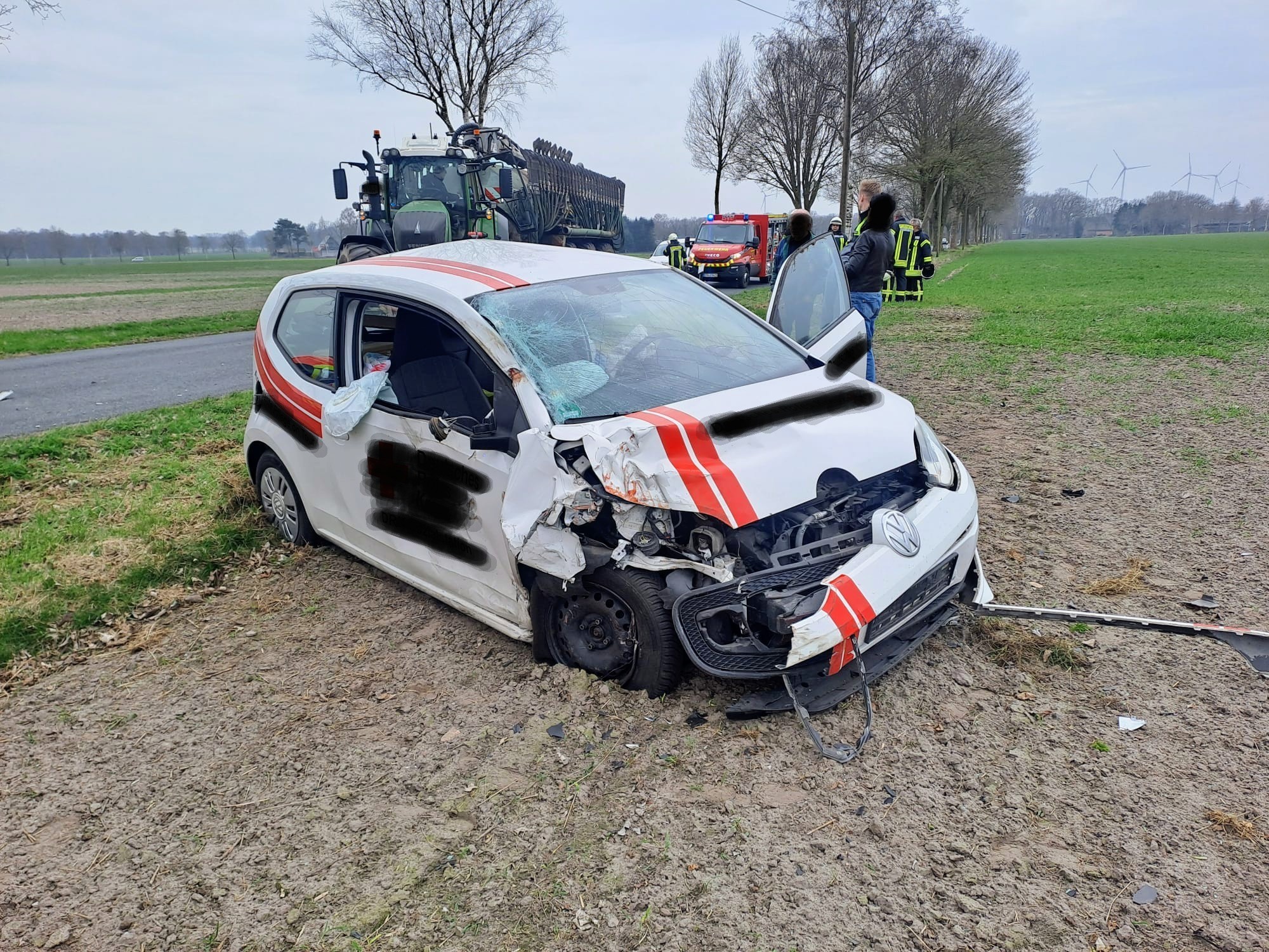 Ein weiß-roter VW steht auf einem Feld. Er ist stark beschädigt.