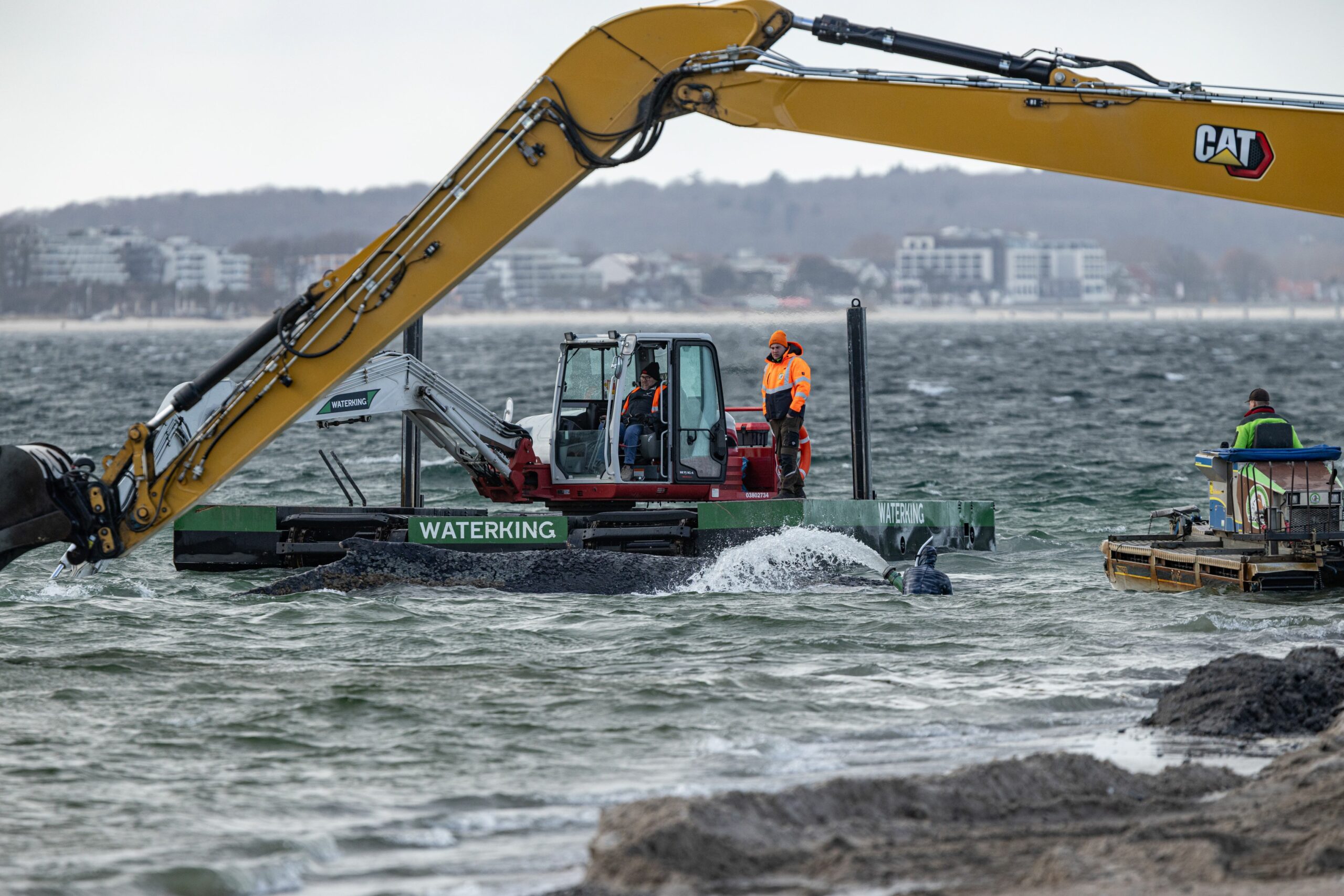 Ein Schwimmbagger arbeitet neben dem gestrandeten Buckelwal vor Timmendorfer Strand.