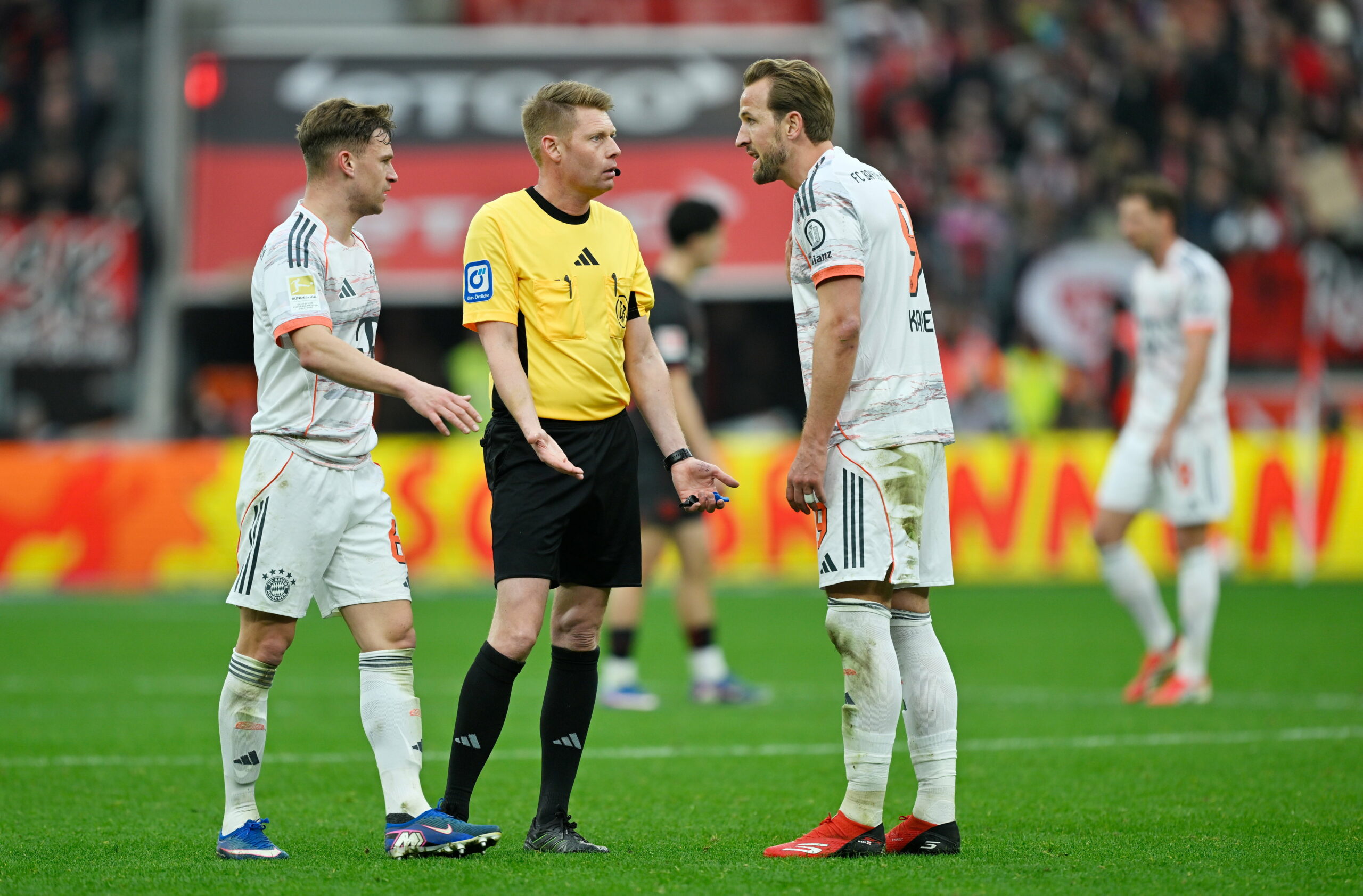 Die Bayern-Stars Joshua Kimmich und Harry Kane diskutieren mit Schiri Christian Dingert