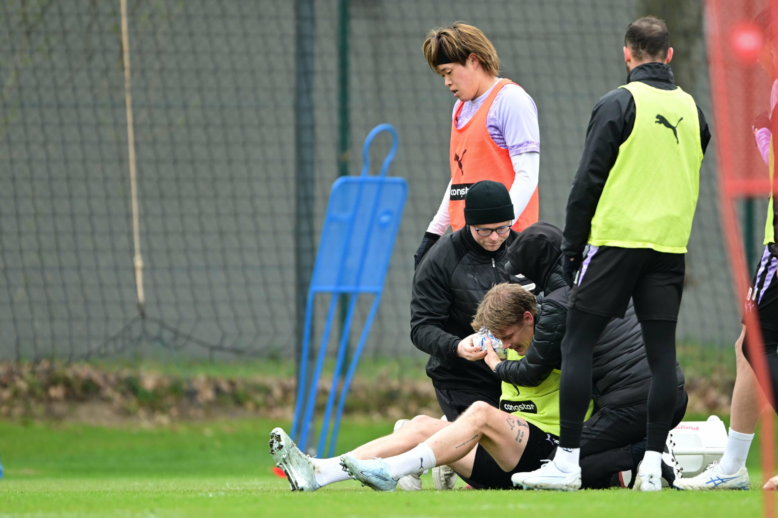 Eric Smith wird im Training behandelt und sitzt auf dem Boden. Tomoya Ando schaut gefasst.