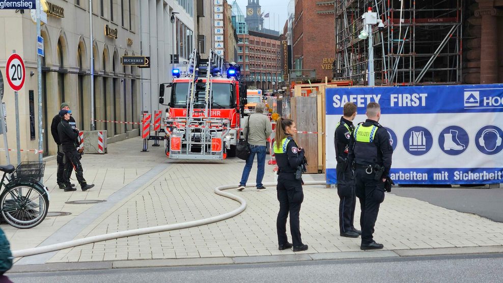 Polizisten stehen vor dem Einsatzwagen der Feuerwehr in der Hamburger Innenstadt.
