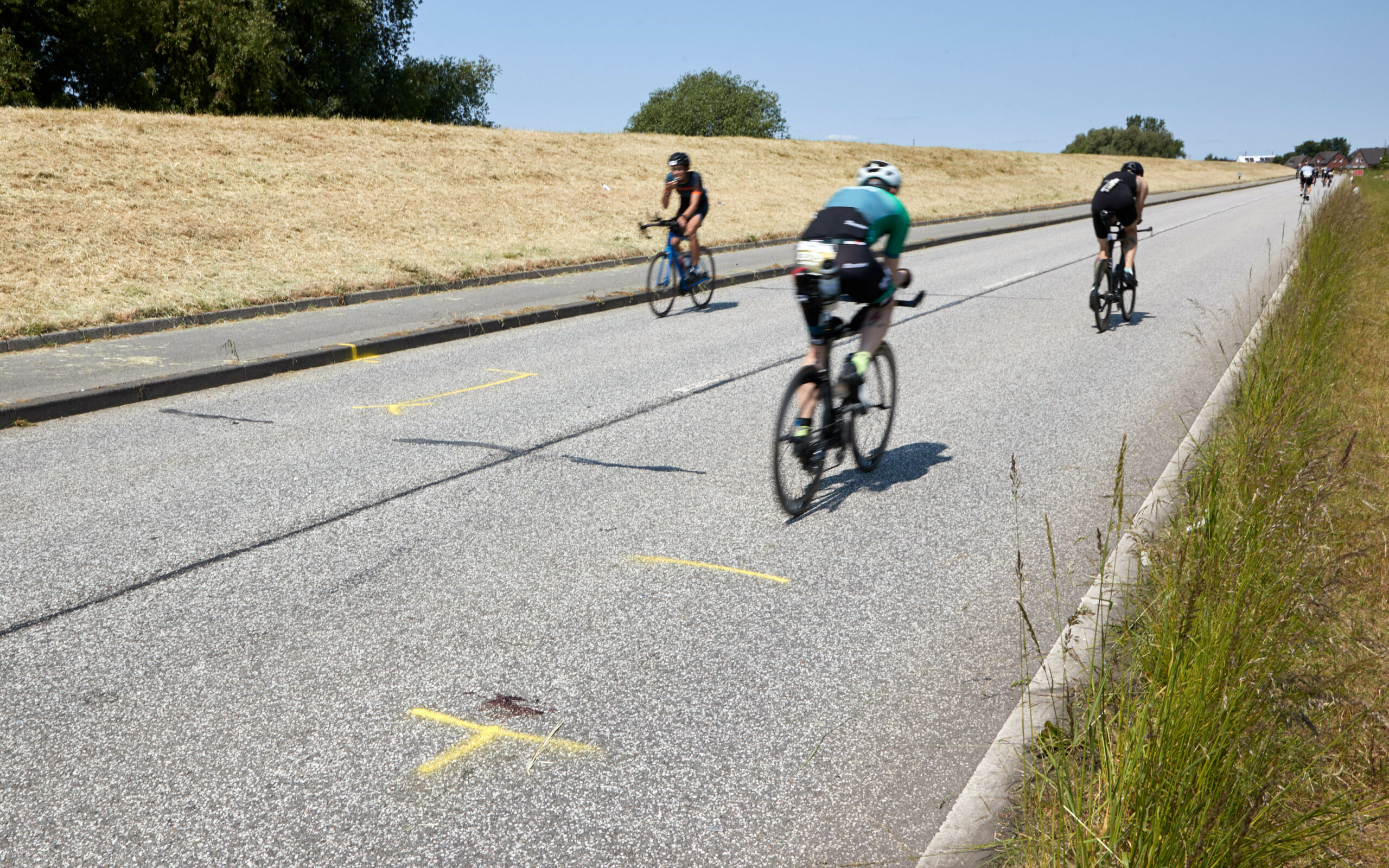 Triathleten fahren auf dem Rad an der Unglückstelle auf dem Gaueter Hauptdeich vorbei.
