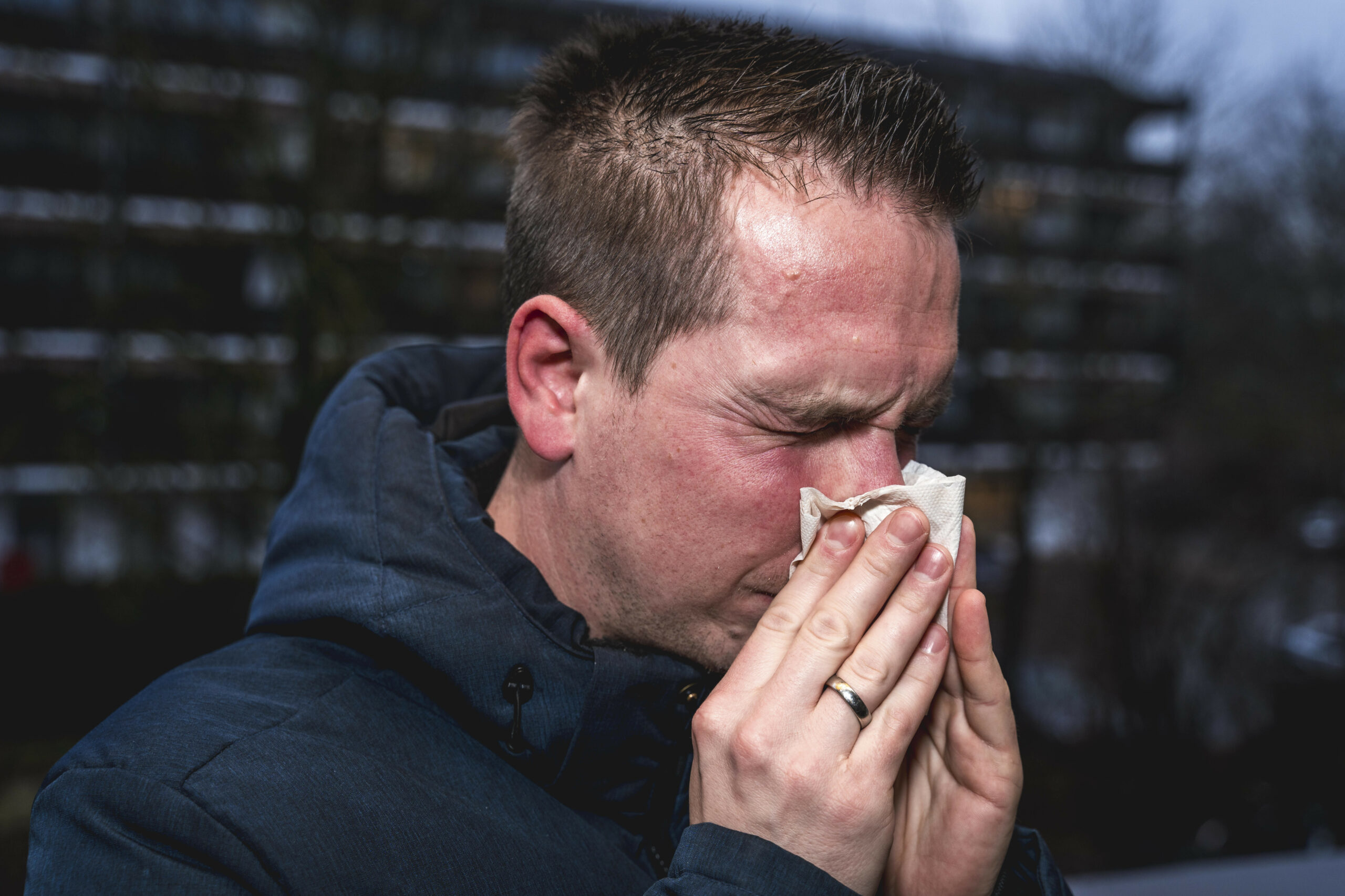 Ein erkälteter Mann putzt sich die Nase.