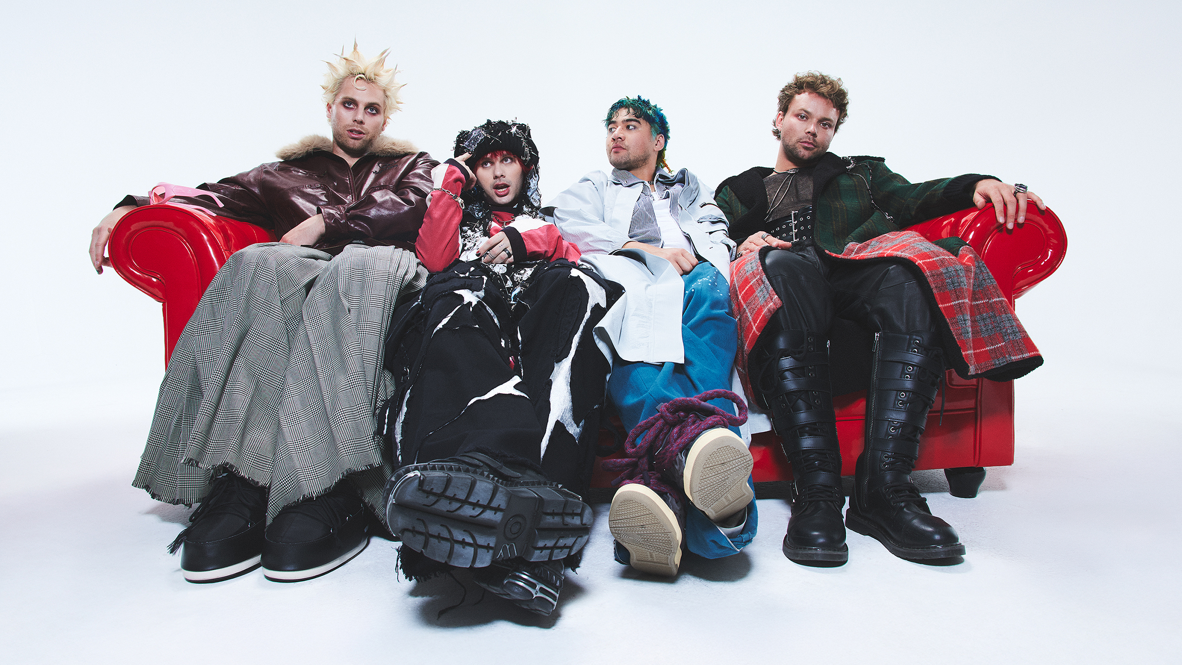 Die vier Bandmitglieder von 5 Seconds Of Summer sitzen auf einem roten Sofa.