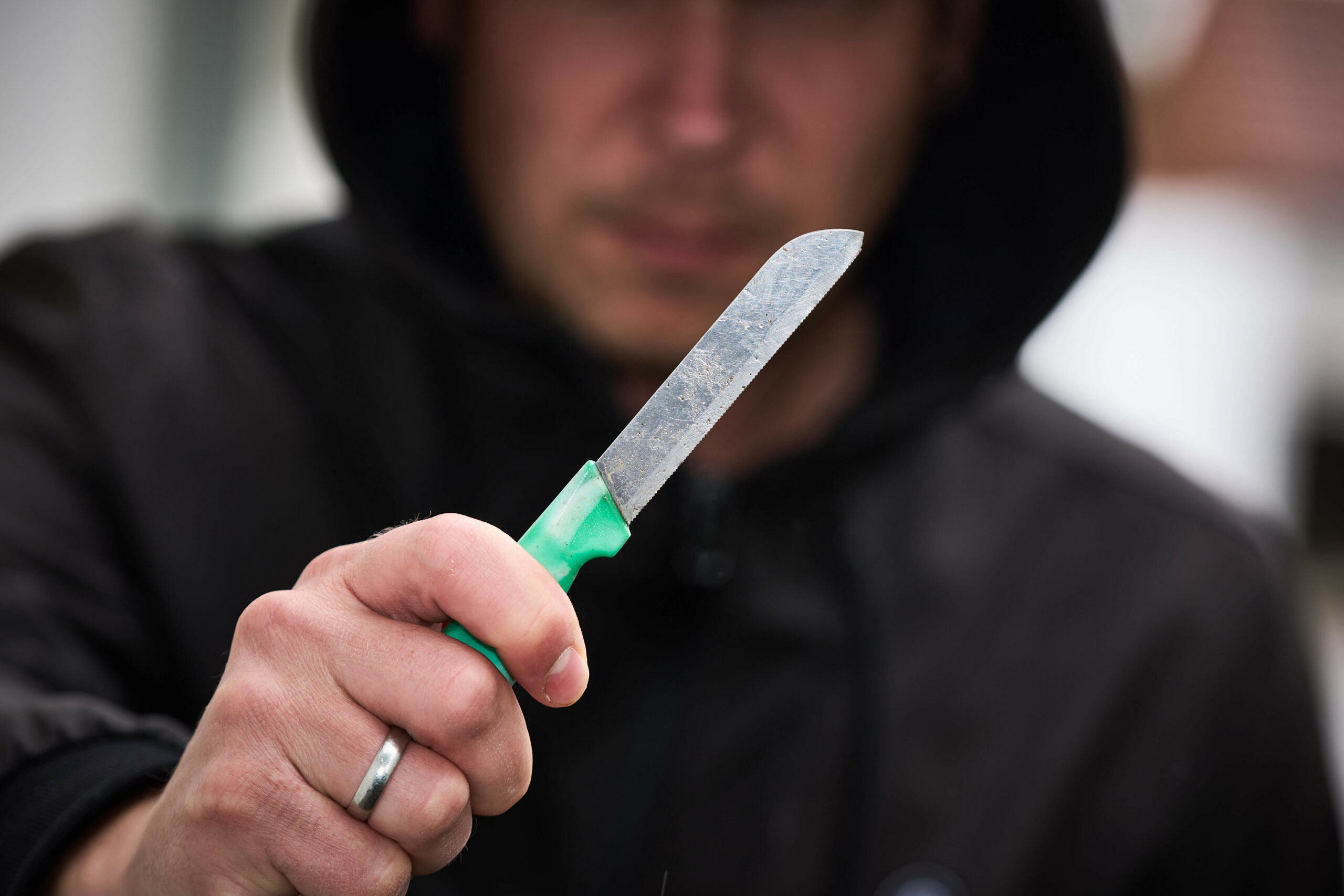 Ein Mann mit Kapuze hält ein Obstmesser in der Hand.