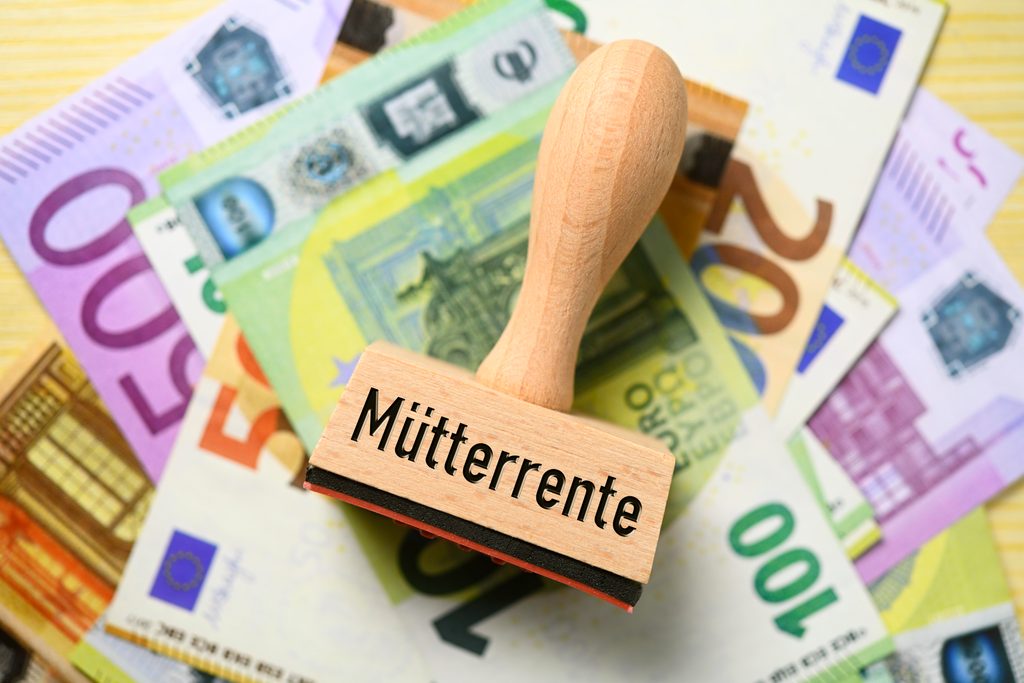 Ein Stempel mit der Aufschrift „Mütterrente“ liegt auf einem Haufen Bargeld.