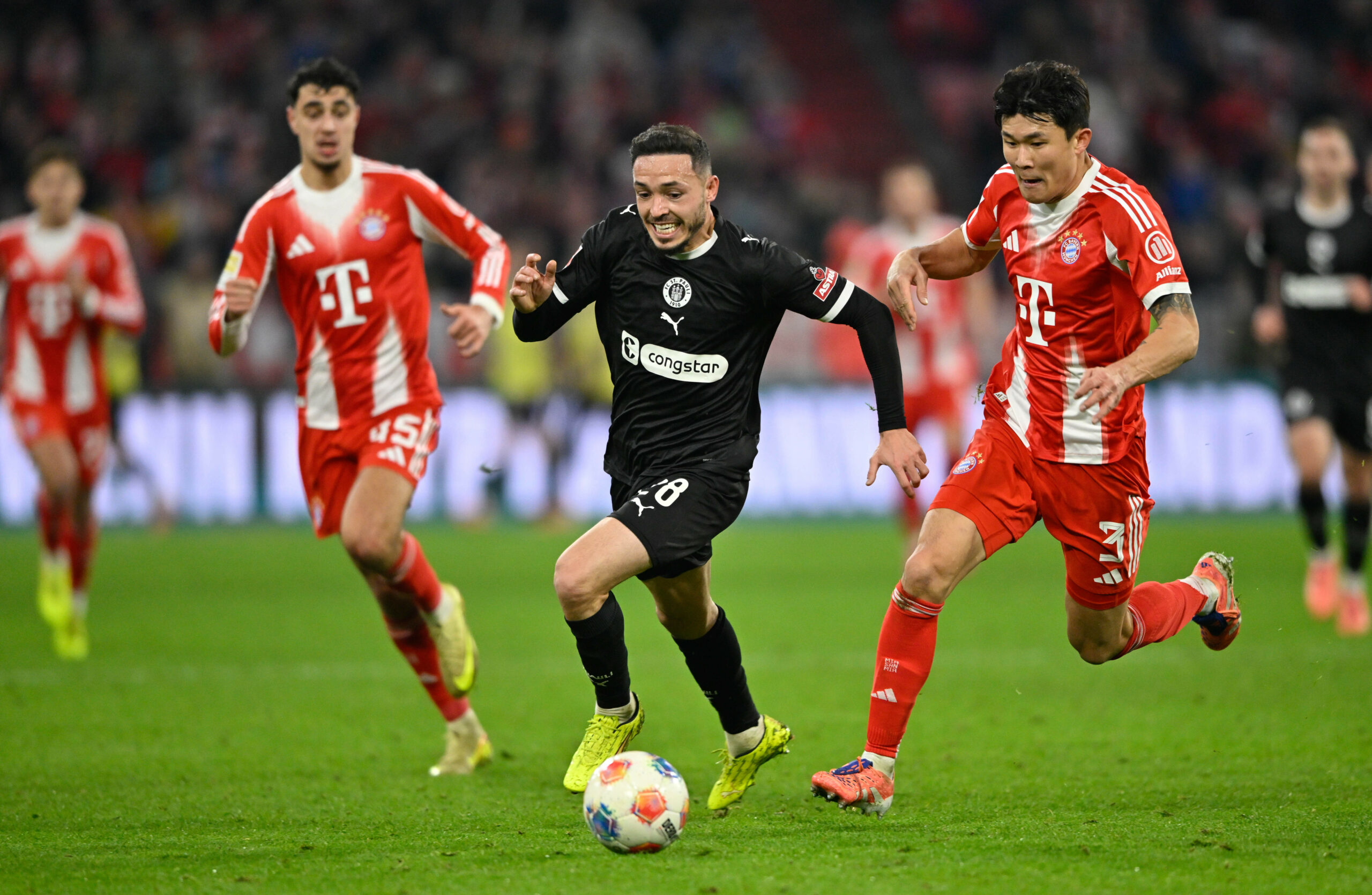 Mathias Pereira Lage vom FC St. Pauli im Zweikampf mit Min-jae Kim vom FC Bayern München