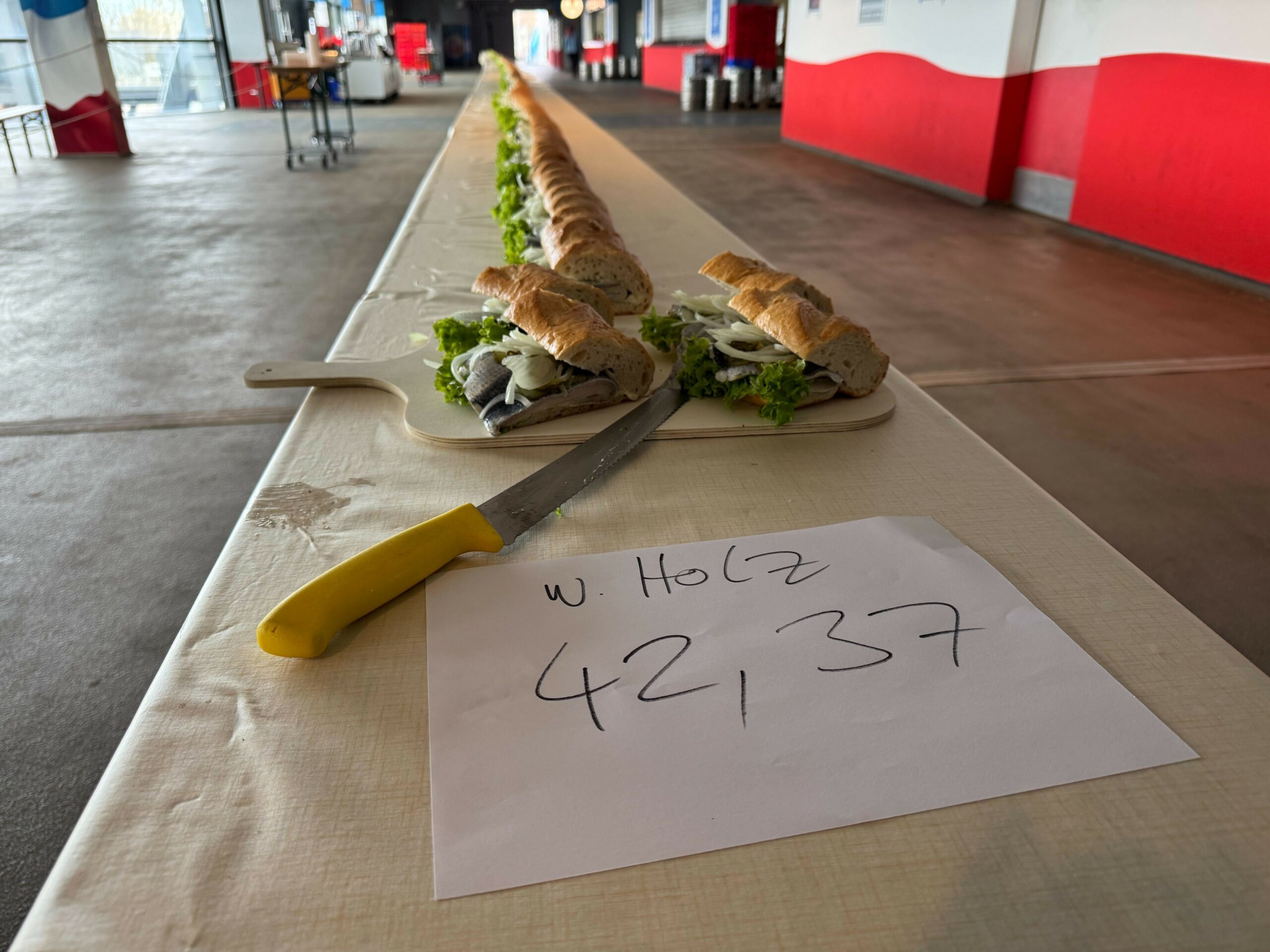 „42,37“ steht auf einem Platt Papier geschrieben, das vor dem langen Fischbrötchen liegt.