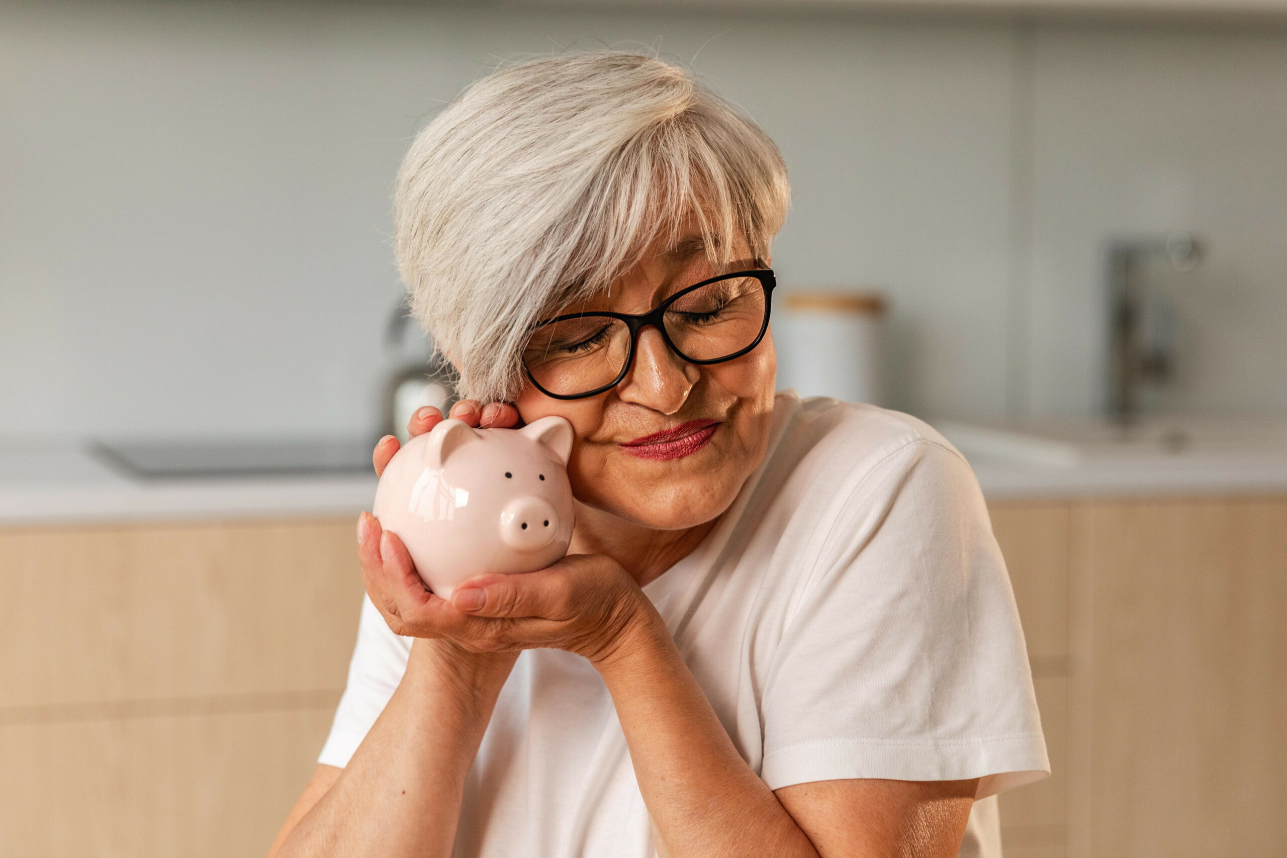 Eine Seniorin hält ein Sparschwein.