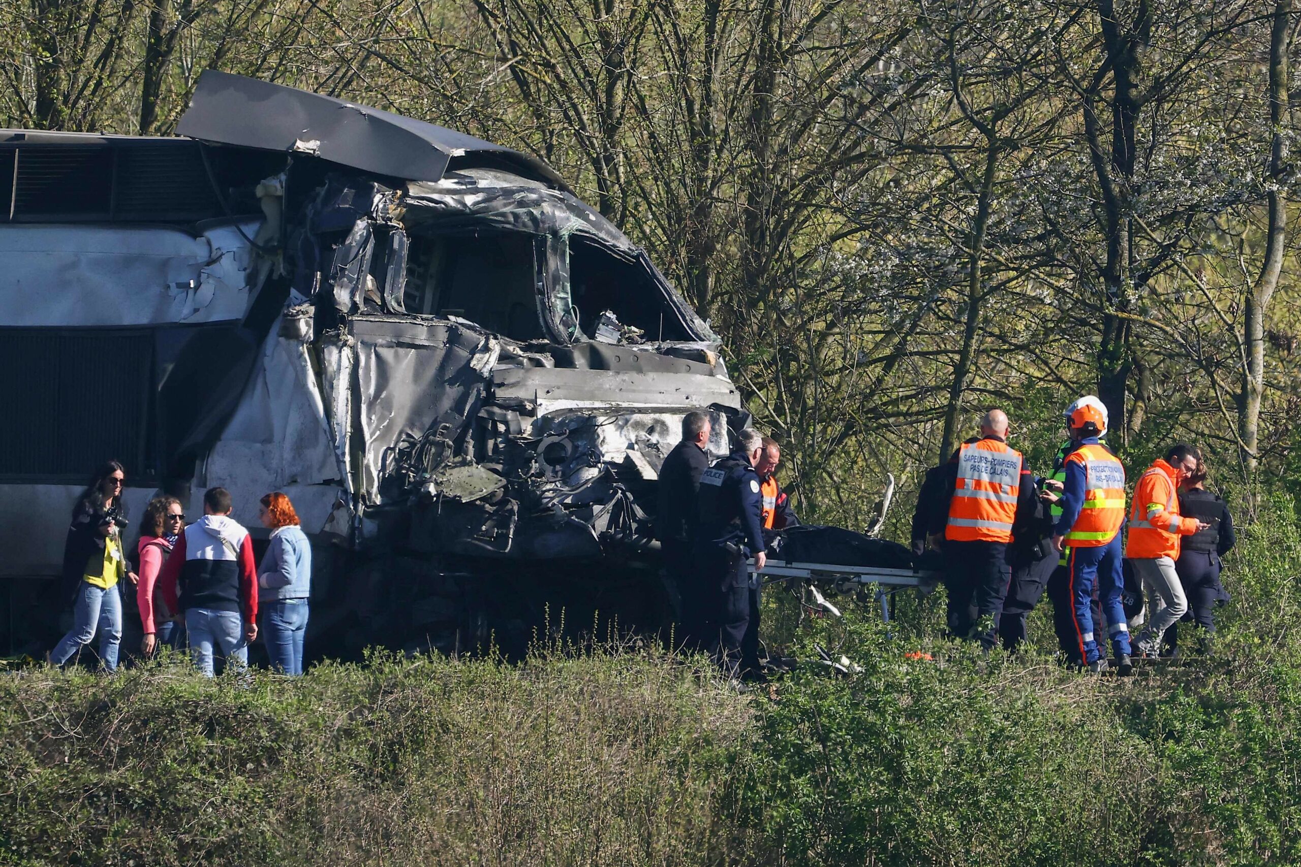 Feuerwehrleute und Polizisten transportieren eine Person aus dem Wrack des TGV-Zuges.
