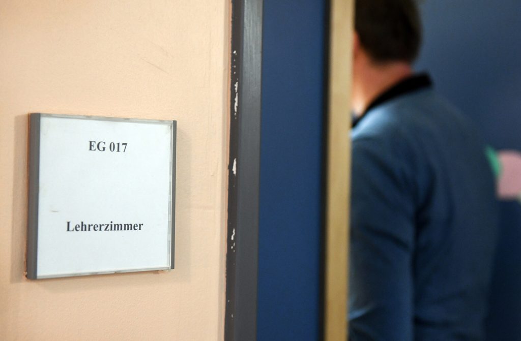 Ein Mann geht an einem Schild vorbei, auf dem „Lehrerzimmer“ steht.