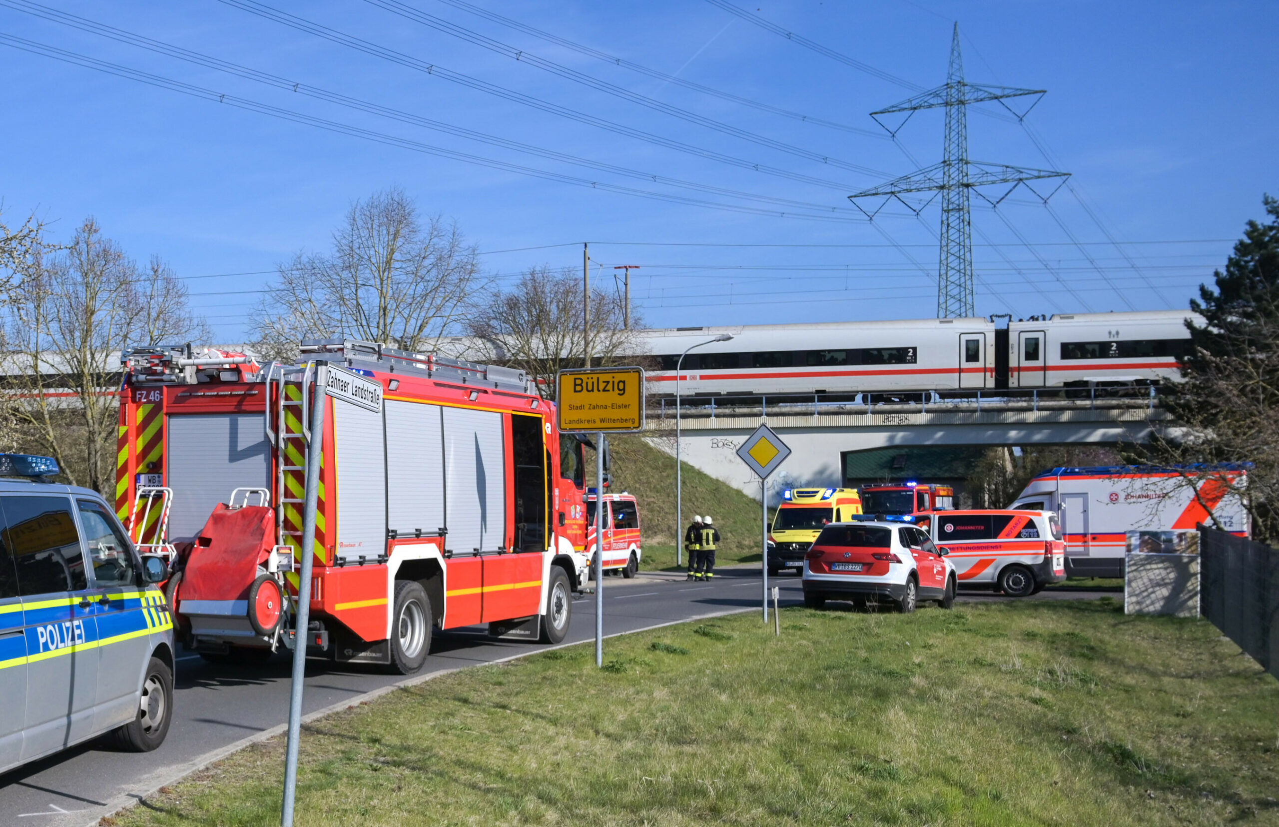 Polizeiwagen und Feuerwehrautos sind vor Ort an Bahngleisen, wo ein ICE zum Stillstand gekommen ist.