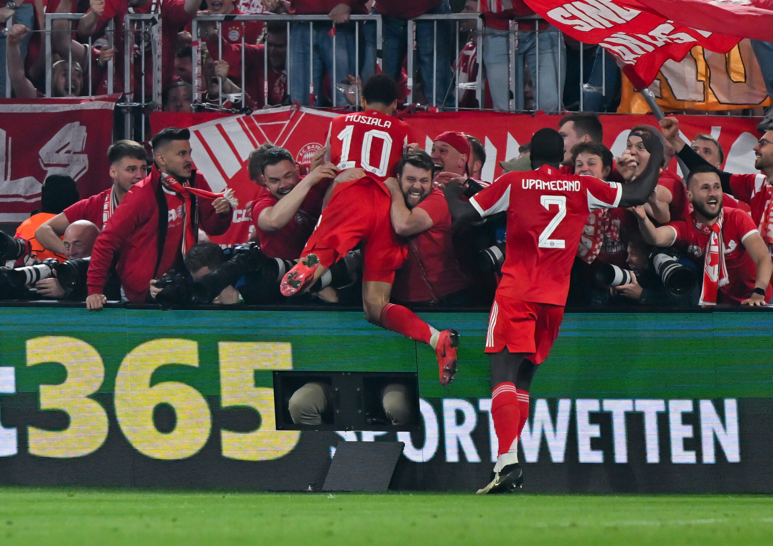 Jamal Musiala springt zum Jubeln in Bayern-Fans am Spielfeldrand