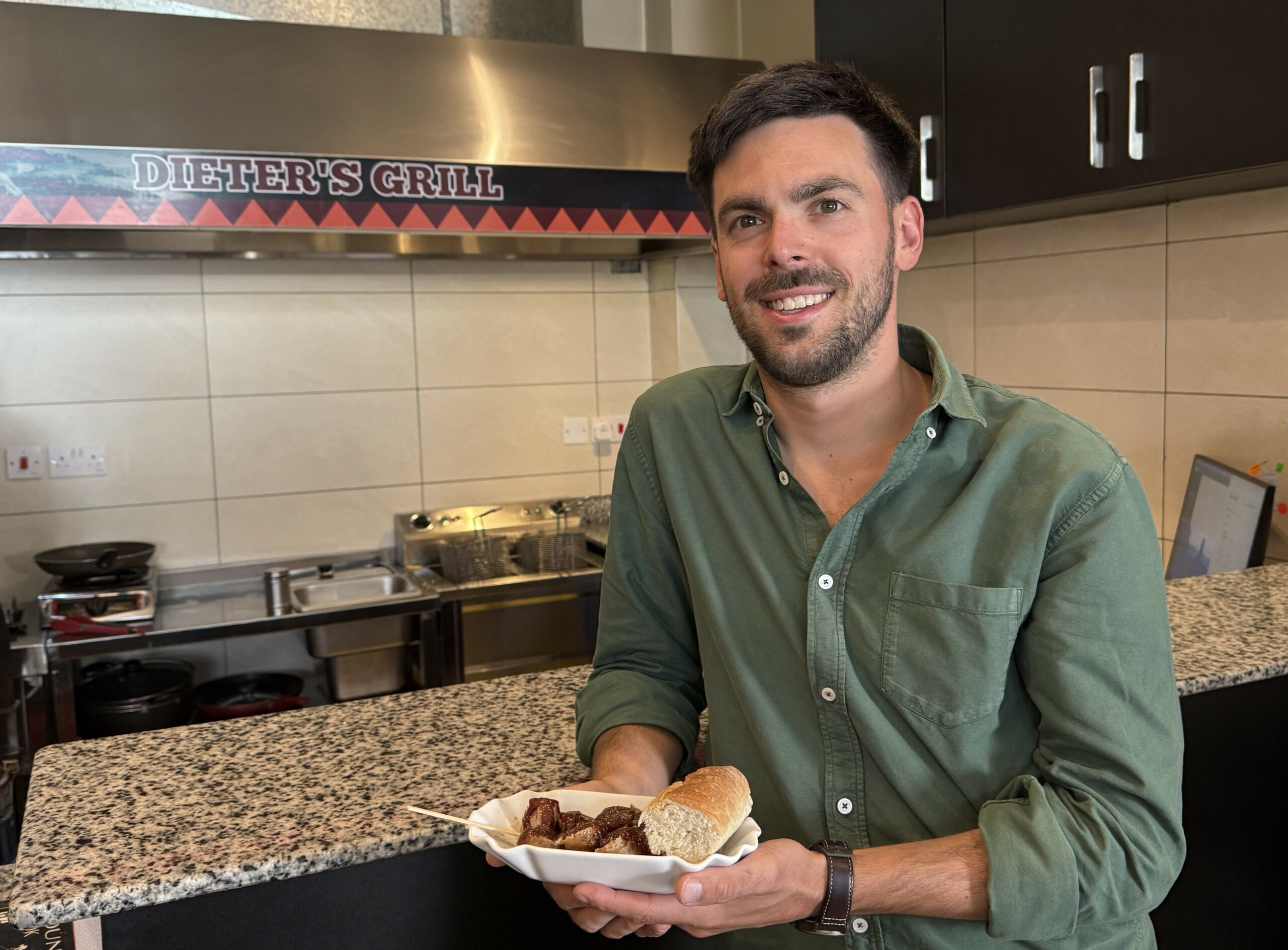 Fabian Förster steht mit einer Currywurst im „Dieters Grill“ in Nairobi.