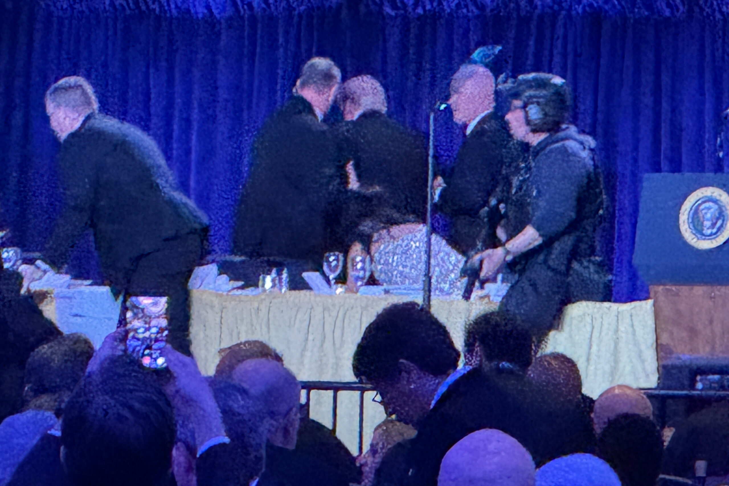 US-Geheimdienstmitarbeiter umringen US-Präsident Donald Trump, dritter von links, als er nach einer Schießerei außerhalb des Ballsaals während des White House Correspondents Dinner am Samstag, 25. April 2026, in Washington von der Bühne gebracht wird.