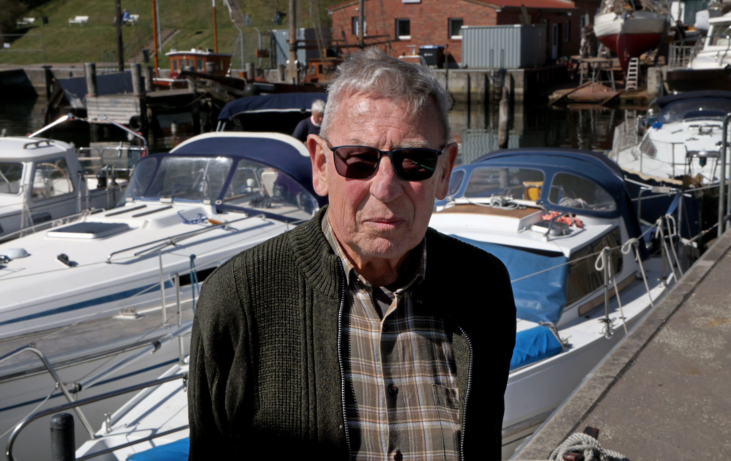 Peter Richter steht in einem Yachthafen.