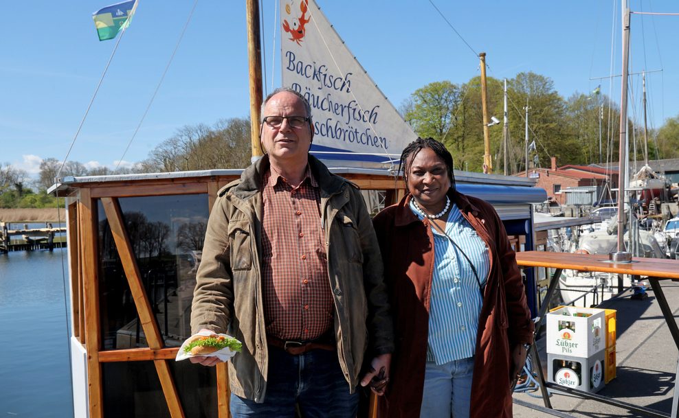 Das Ehepaar Wagner steht in einem Hafen vor einem Fischkutter.