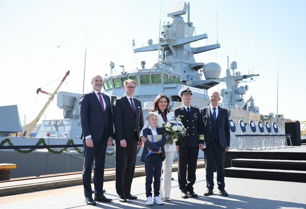 Eine Gruppe an Menschen steht am Kai auf der Werft Blohm+Voss im Hamburger Hafen vor einer Korvette.