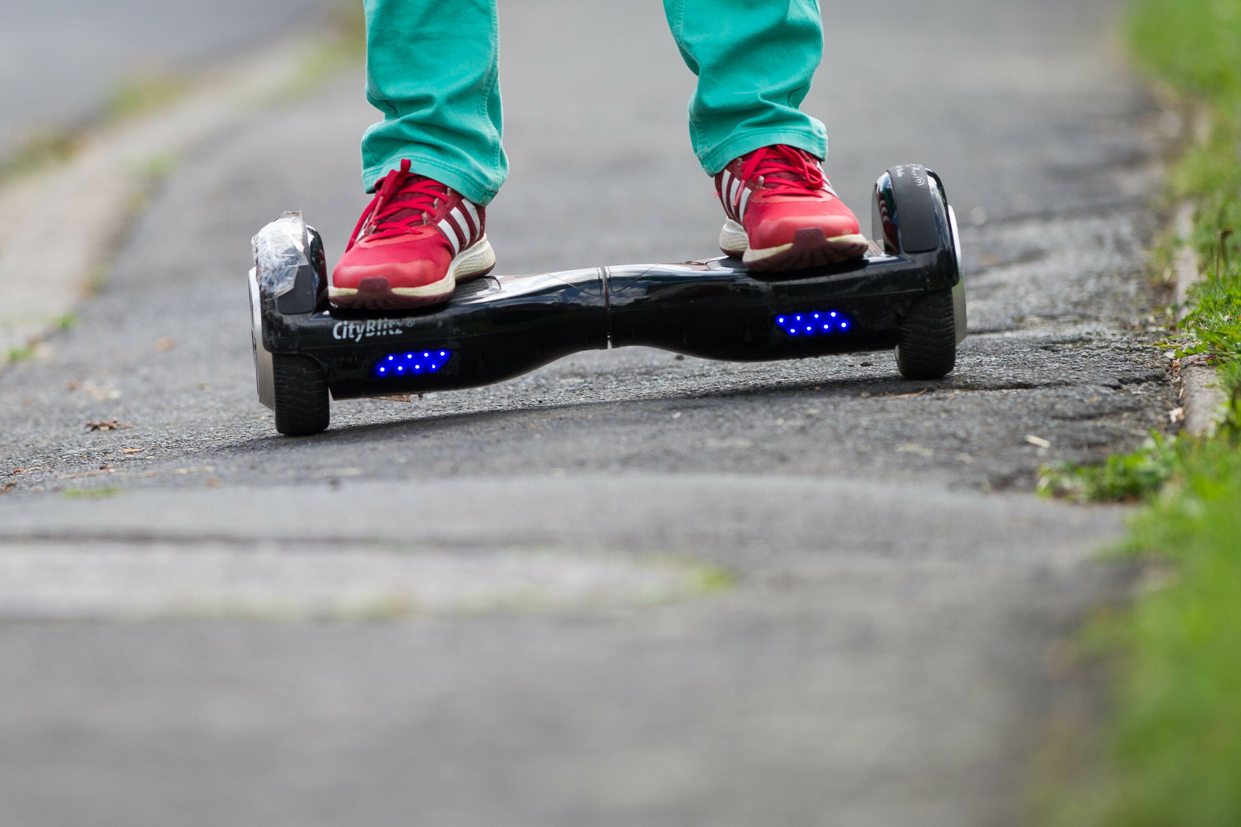 Ein Junge fährt mit einem Hoverboard auf einem Gehweg.