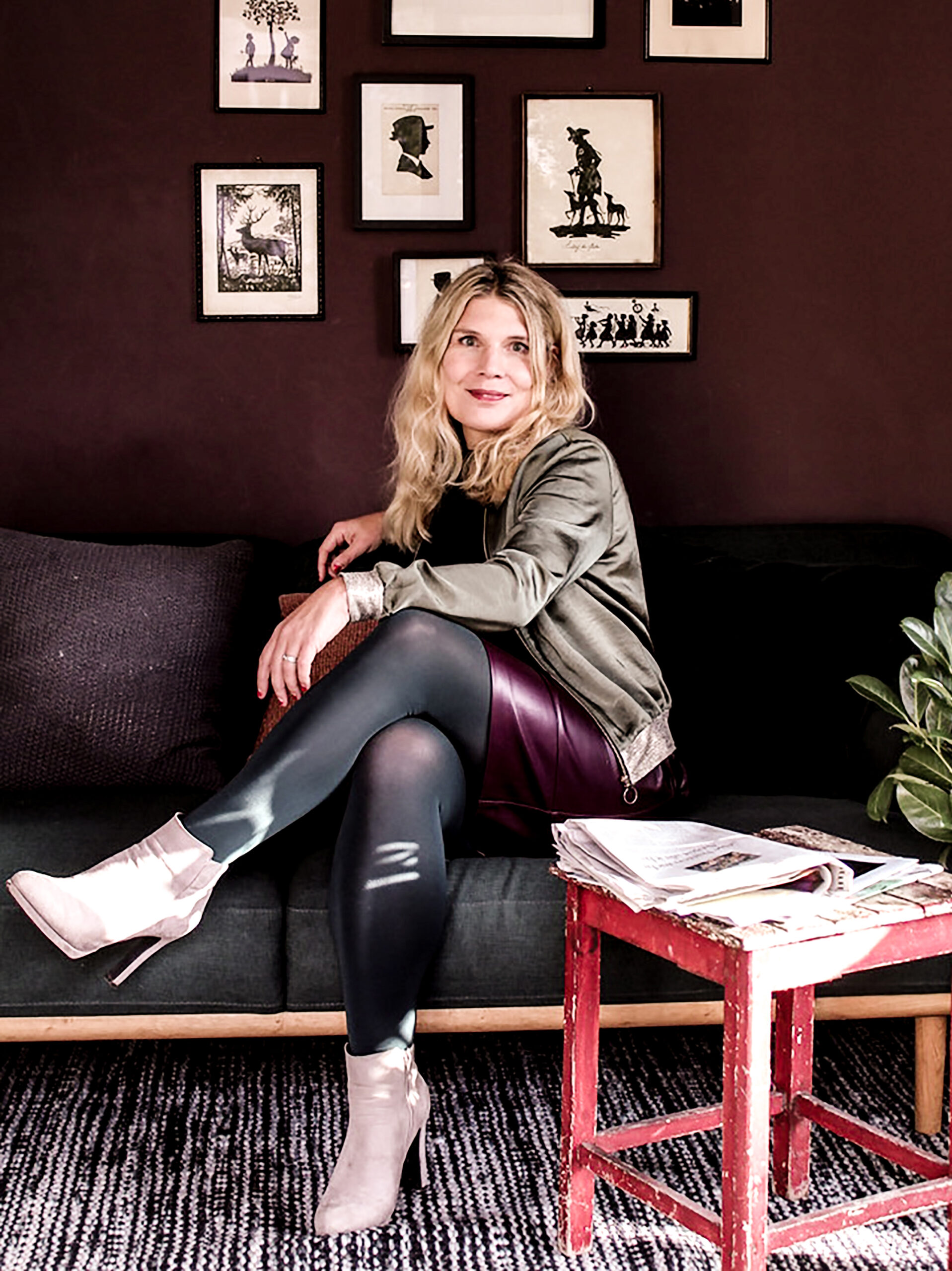 Eine Frau sitzt auf einem Sofa vor einer violett gestrichenen Wand.