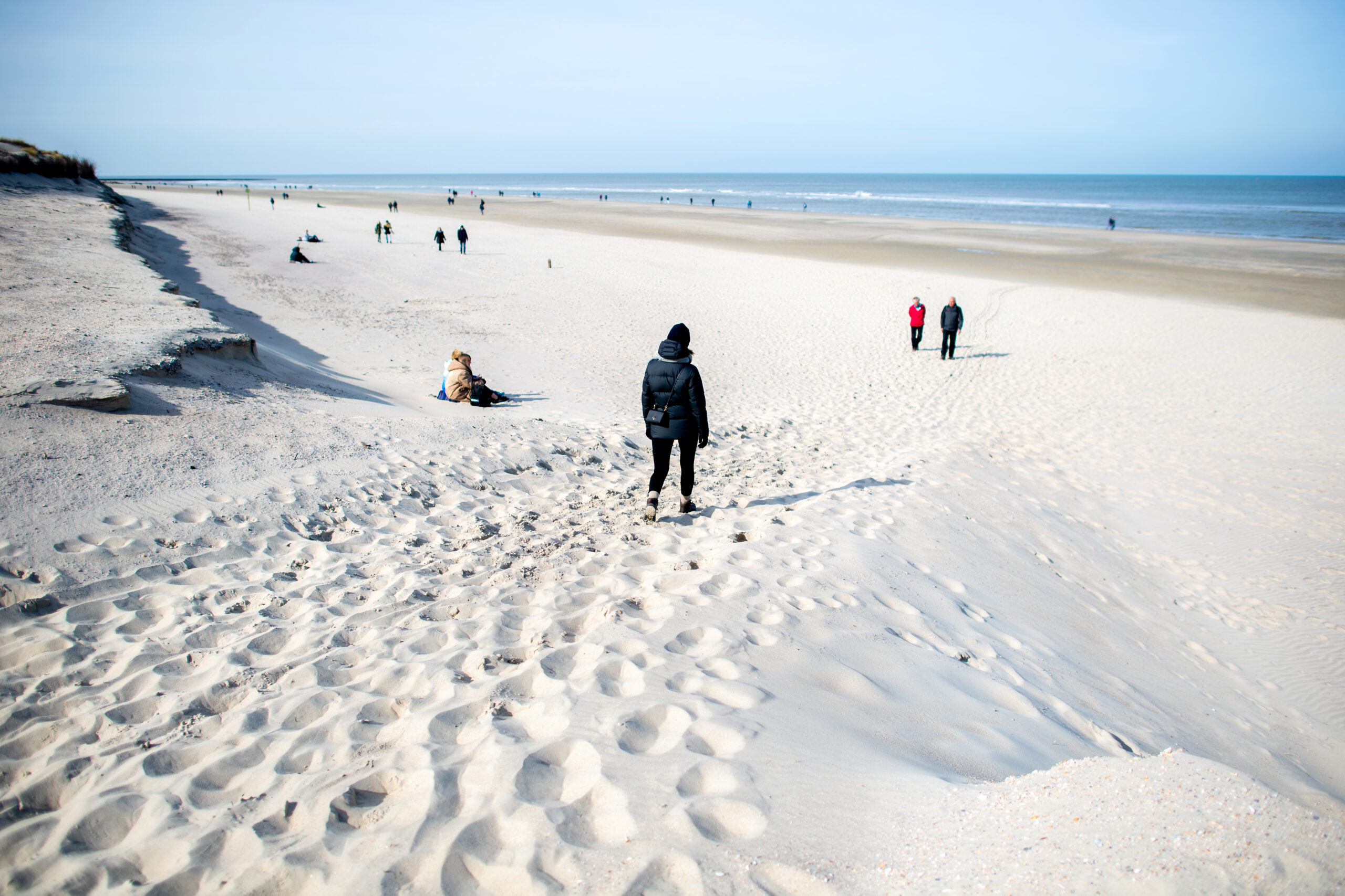 Spaziergänger gehen am Strandabschnitt "Weiße Düne" nahe der Abbruchkante entlang.